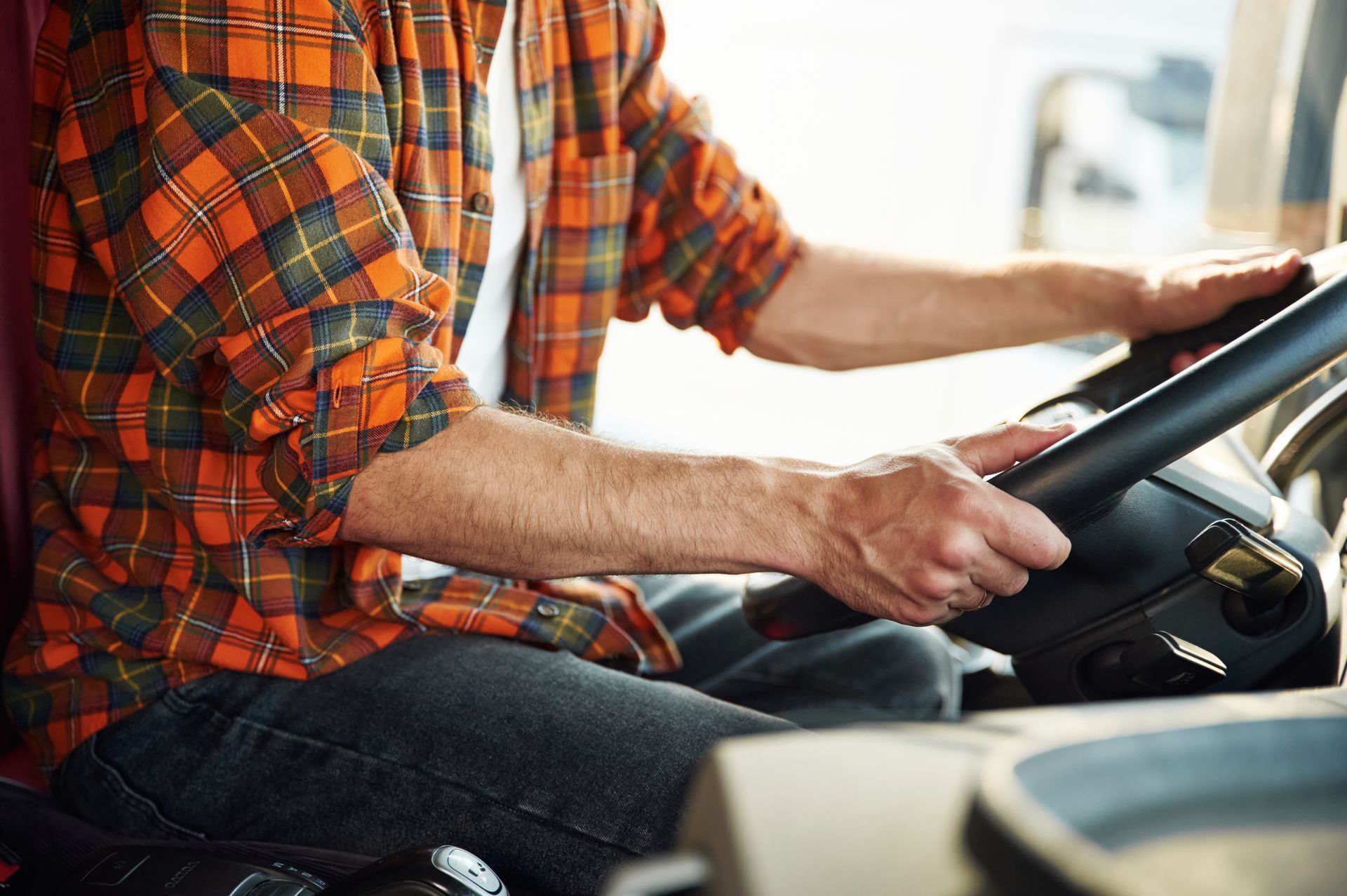 A man is sitting in the driver 's seat of a truck holding the steering wheel.