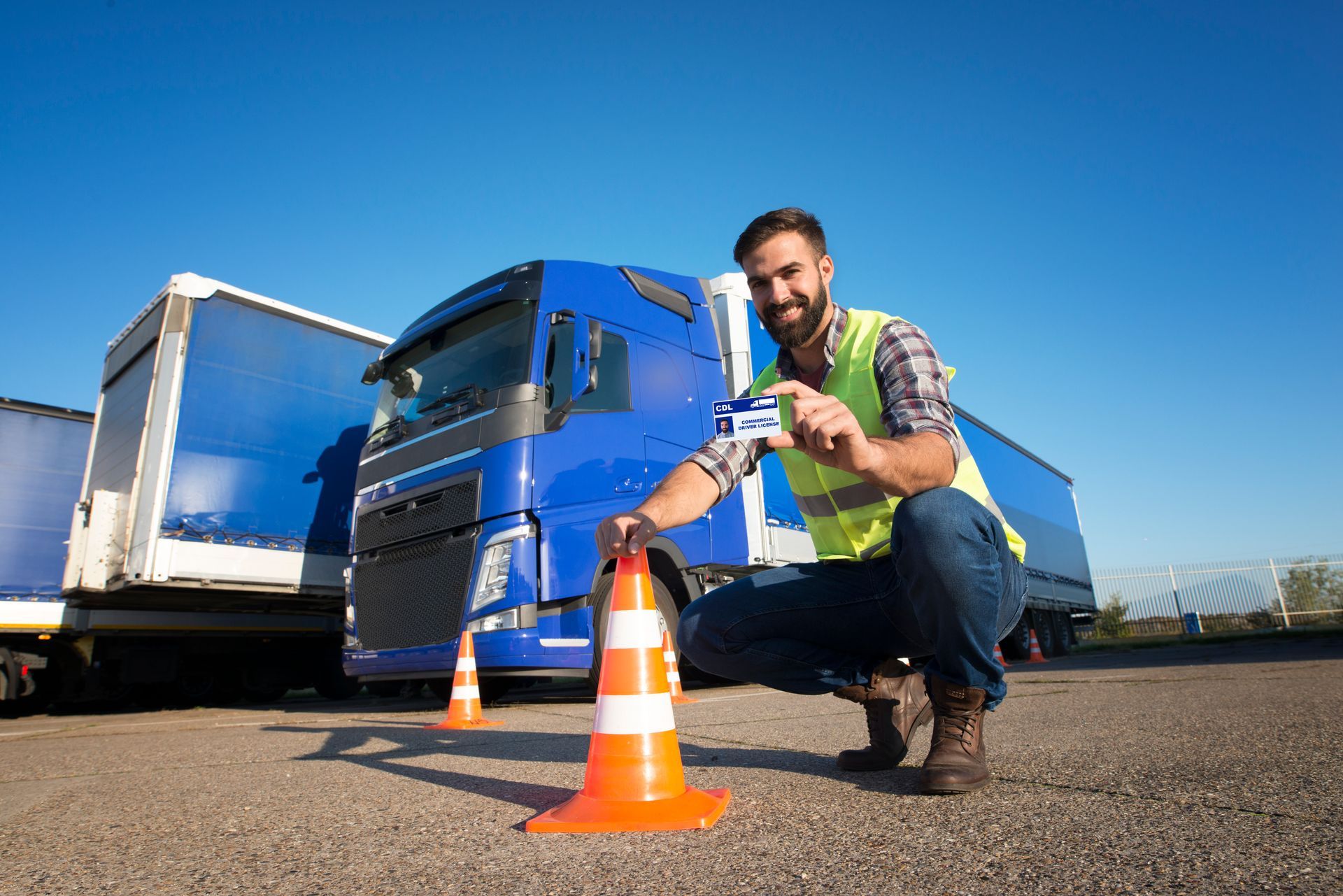 a man is kneeling down next to a traffic cone in front of a truck .