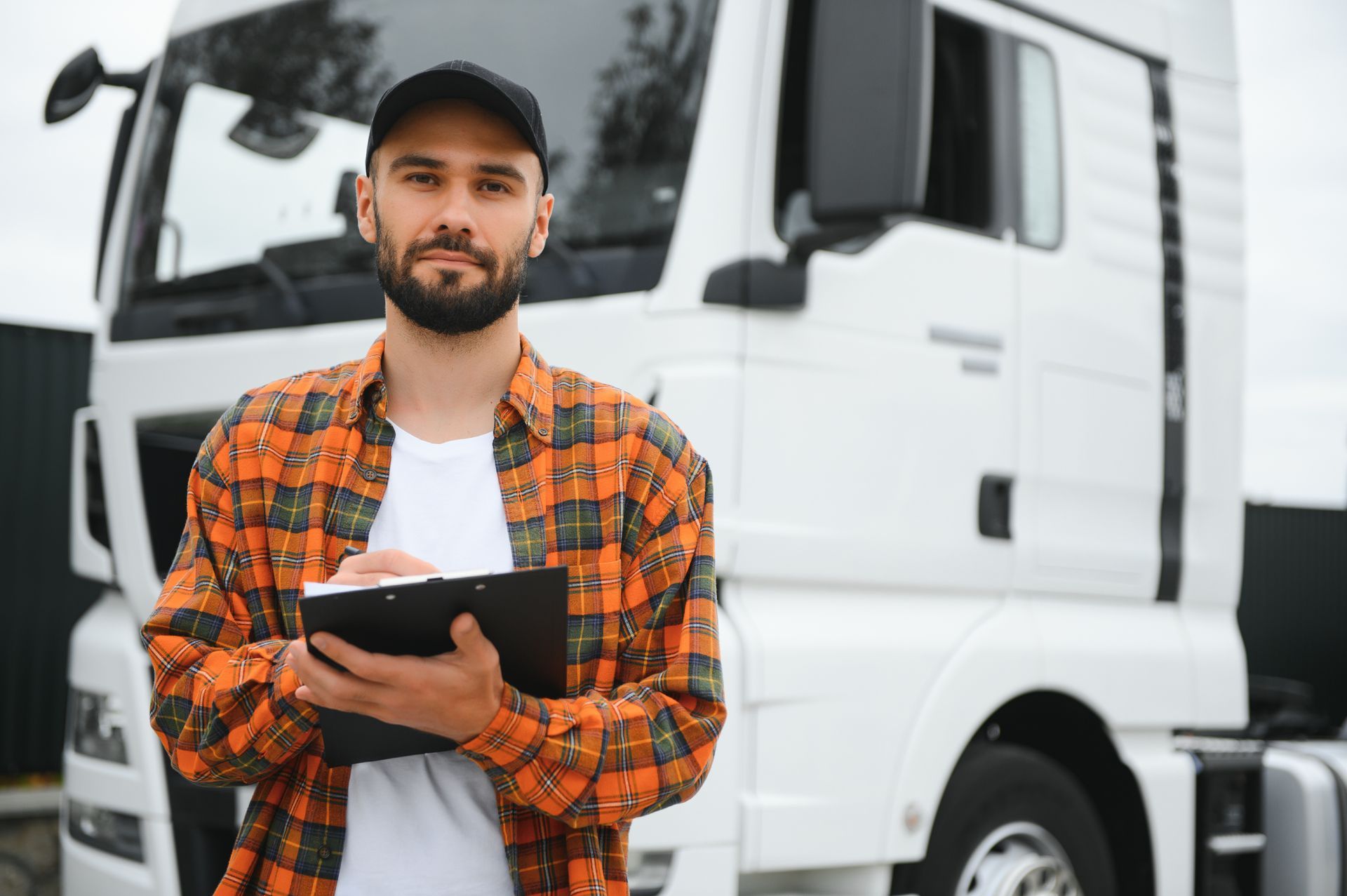 a man is standing in front of a truck holding a clipboard .