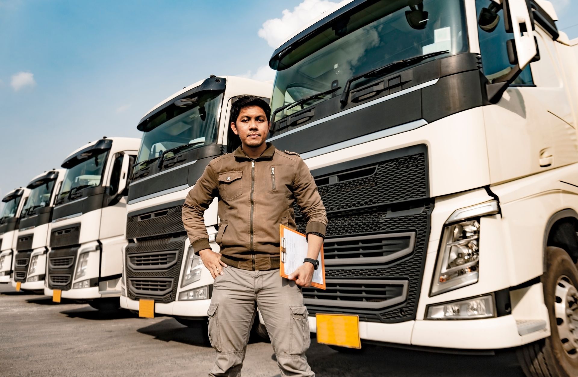 a man is standing in front of a row of semi trucks .