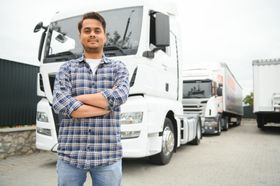 a man is standing in front of a white truck with his arms crossed .