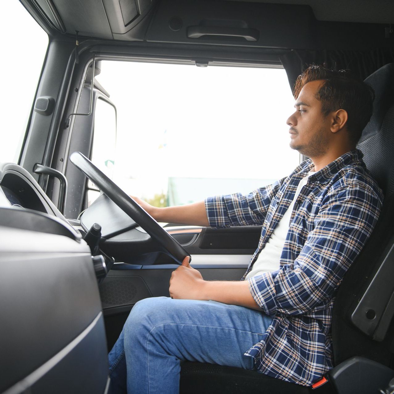 a man in a plaid shirt is driving a truck