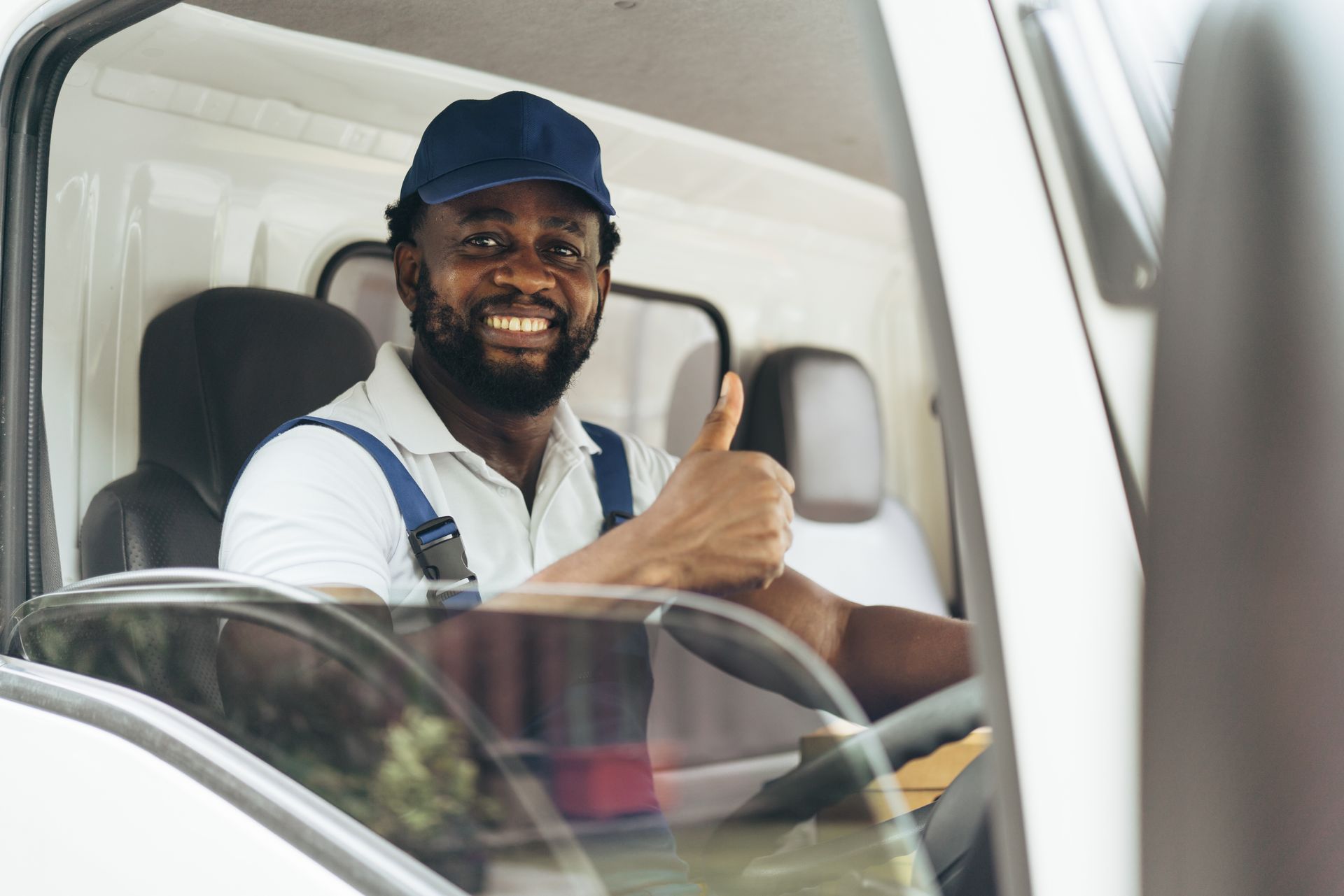 A man is sitting in the driver 's seat of a truck and giving a thumbs up.