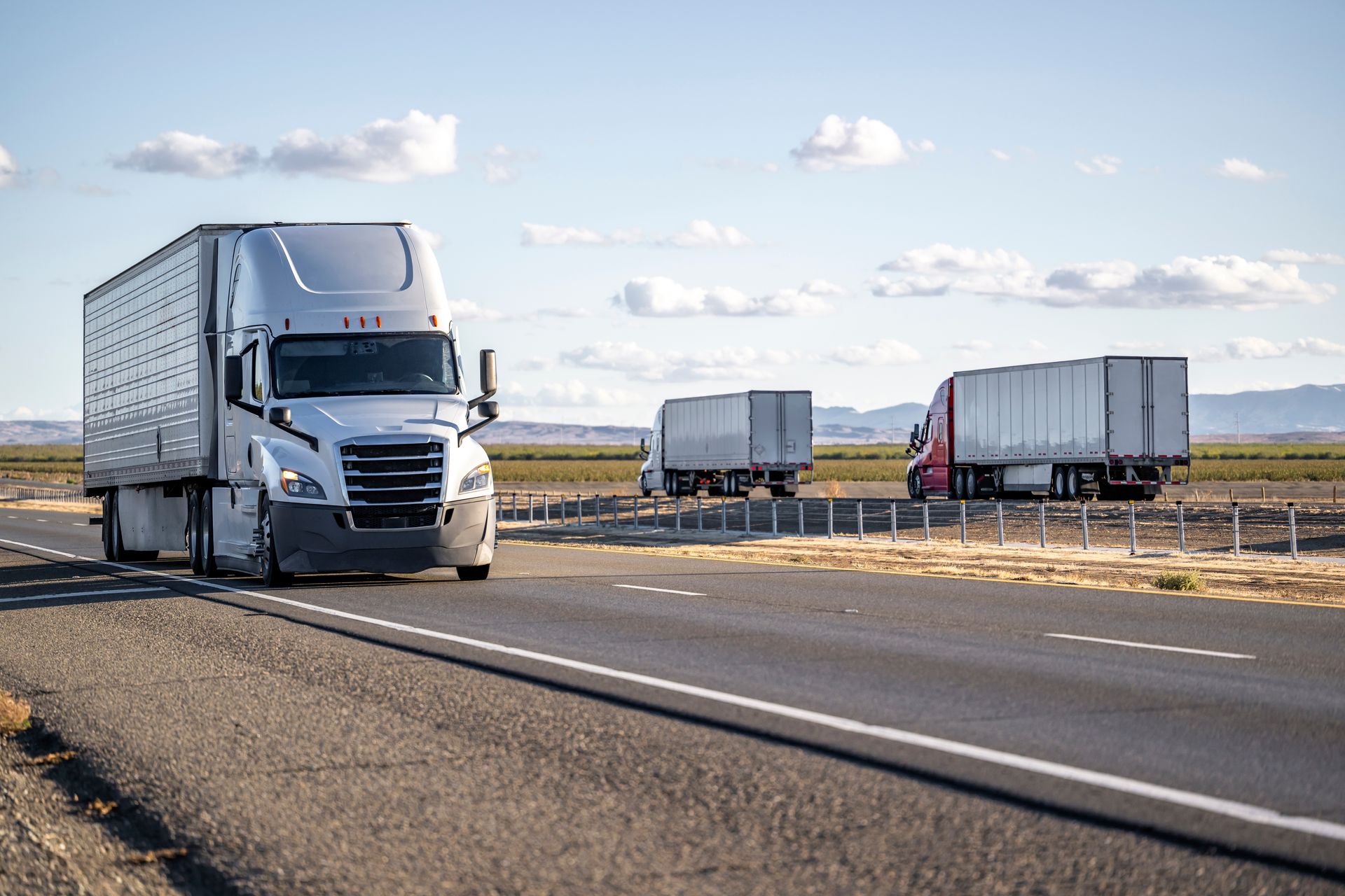 a row of white trucks are parked in a parking lot .