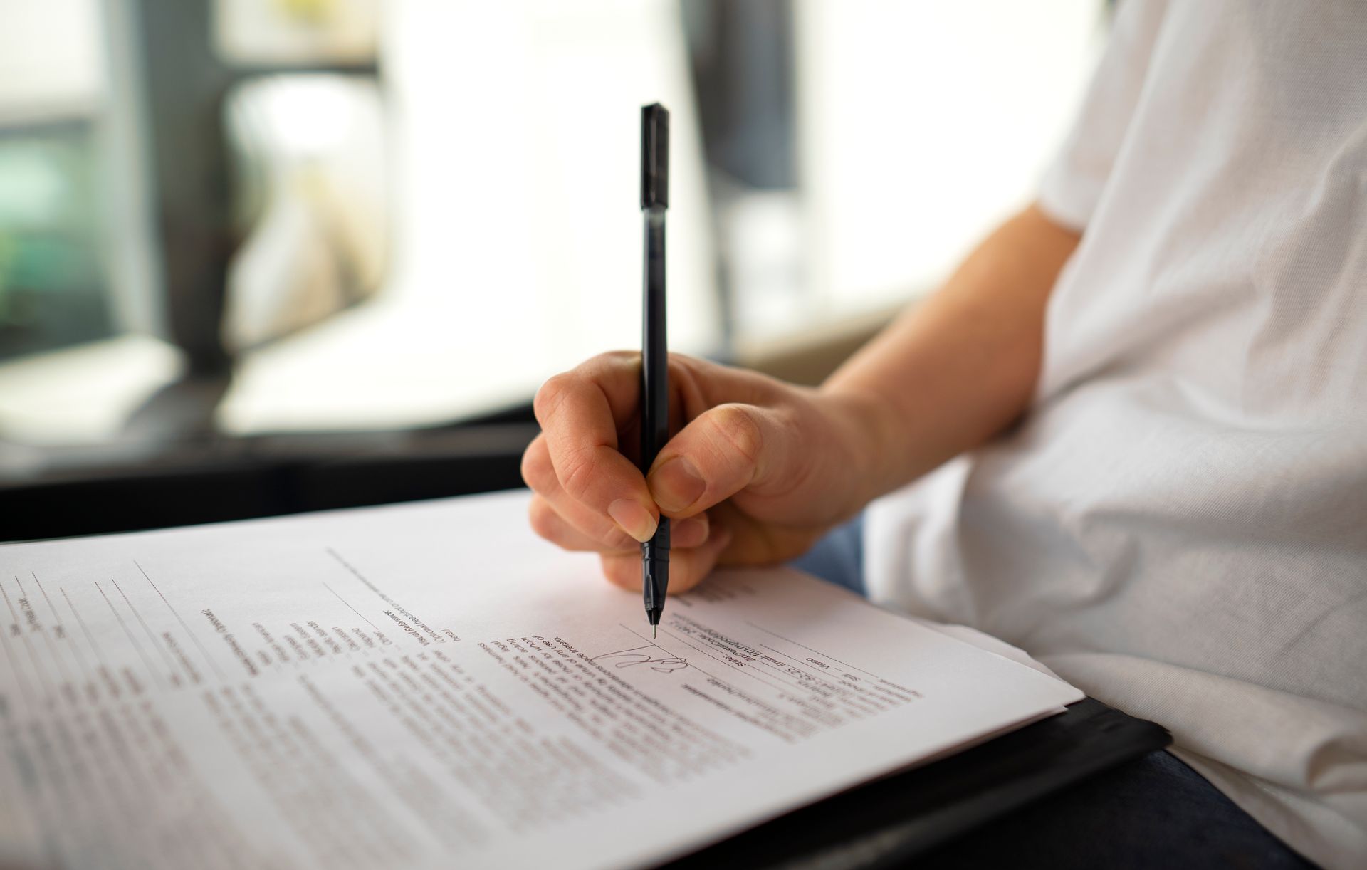 A person is writing on a piece of paper with a pen.