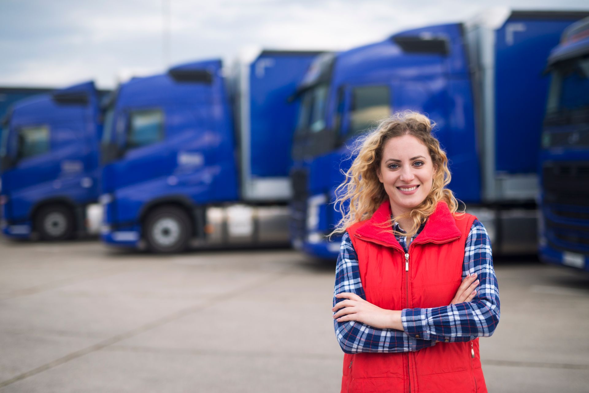 a woman is standing in front of a row of blue trucks .
