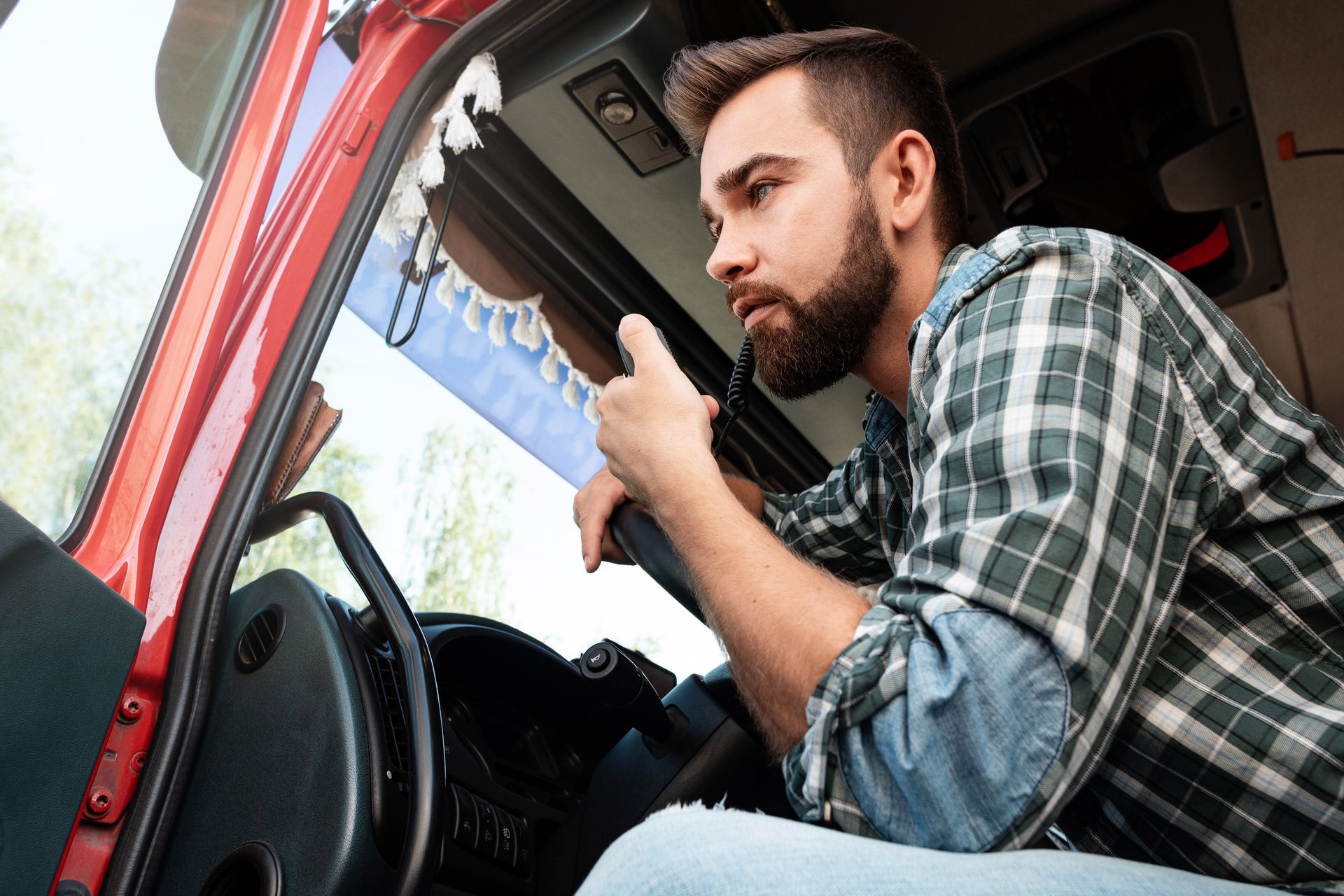 a man is sitting in the driver 's seat of a truck talking on a walkie talkie .