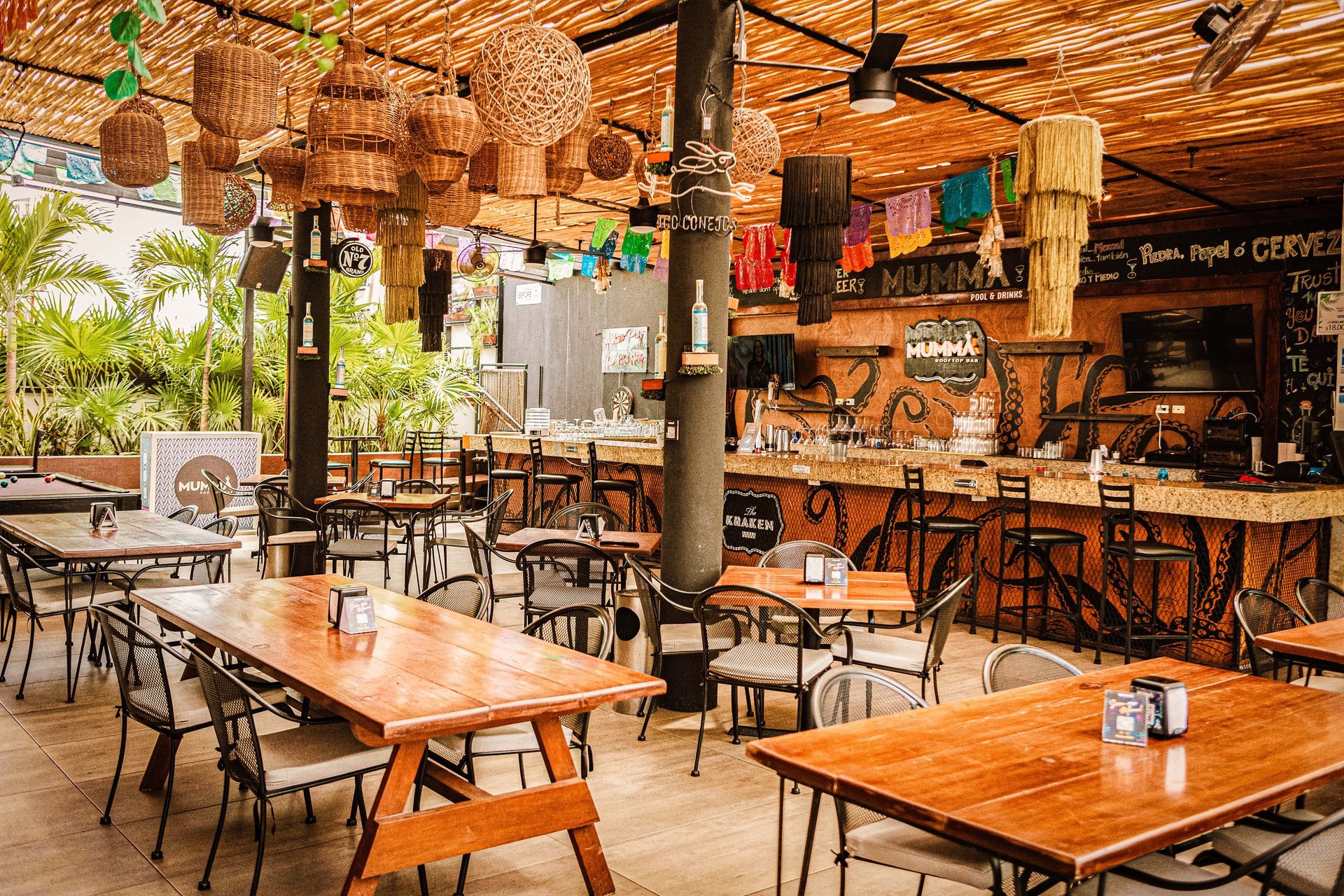 Outdoor restaurant with wooden tables, bar, and woven decorations.