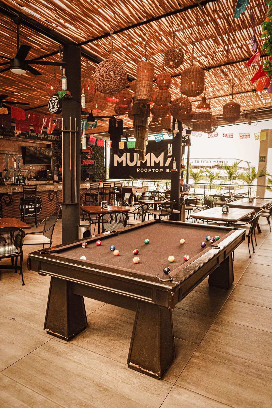 A pool table is sitting under a canopy in a restaurant.