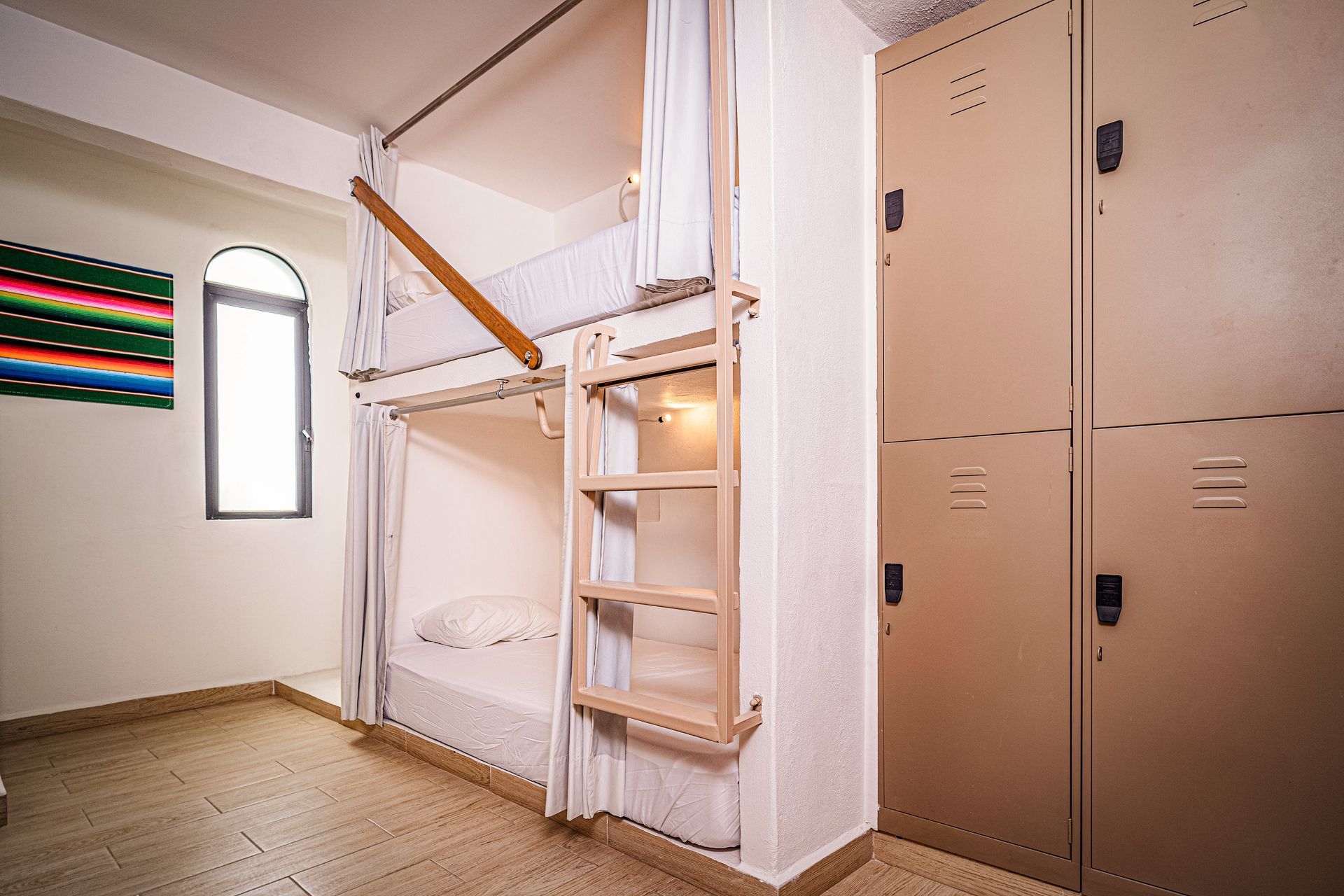 A bunk bed with a ladder in a room with lockers.