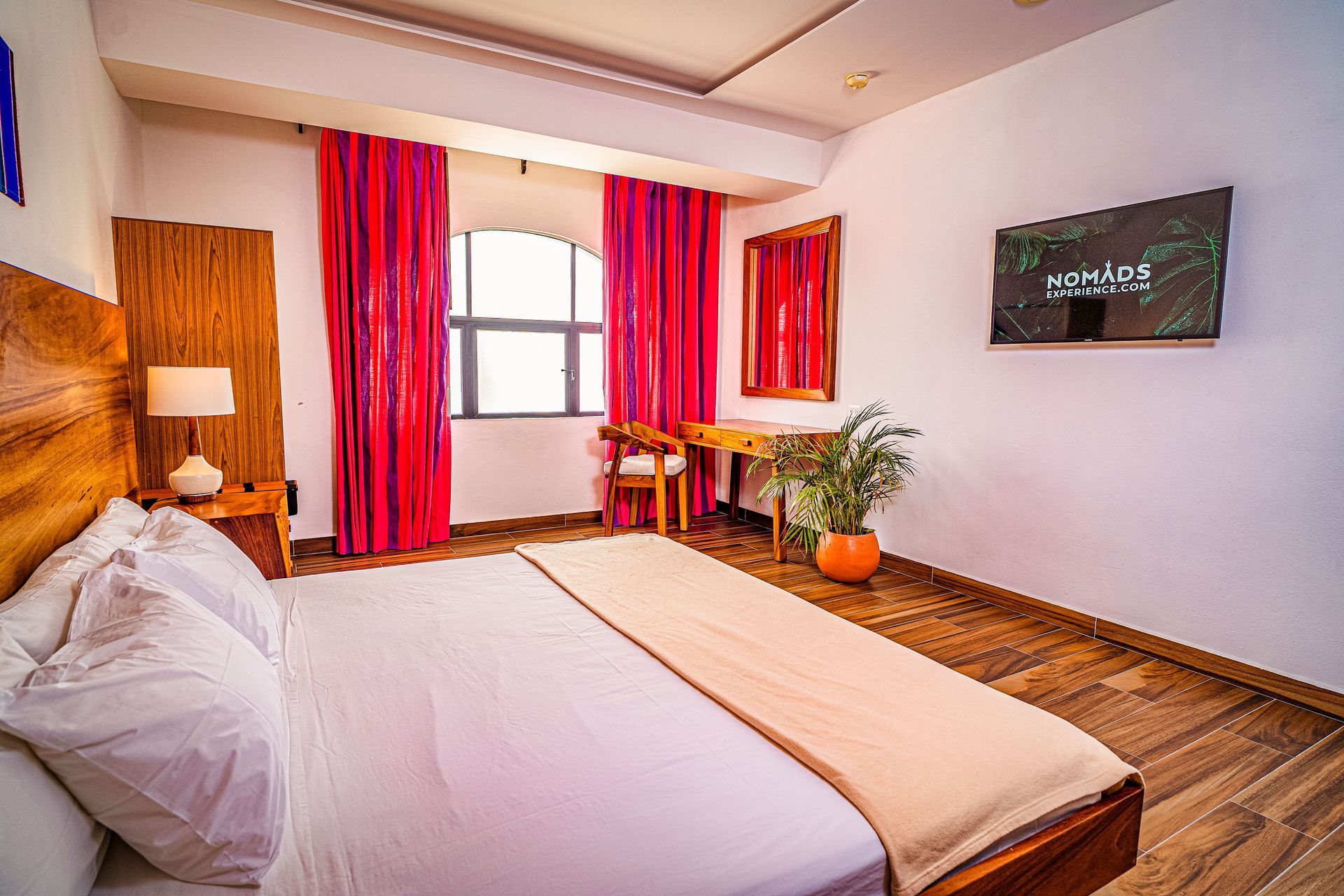 A hotel room with a bed , desk , chair and television.