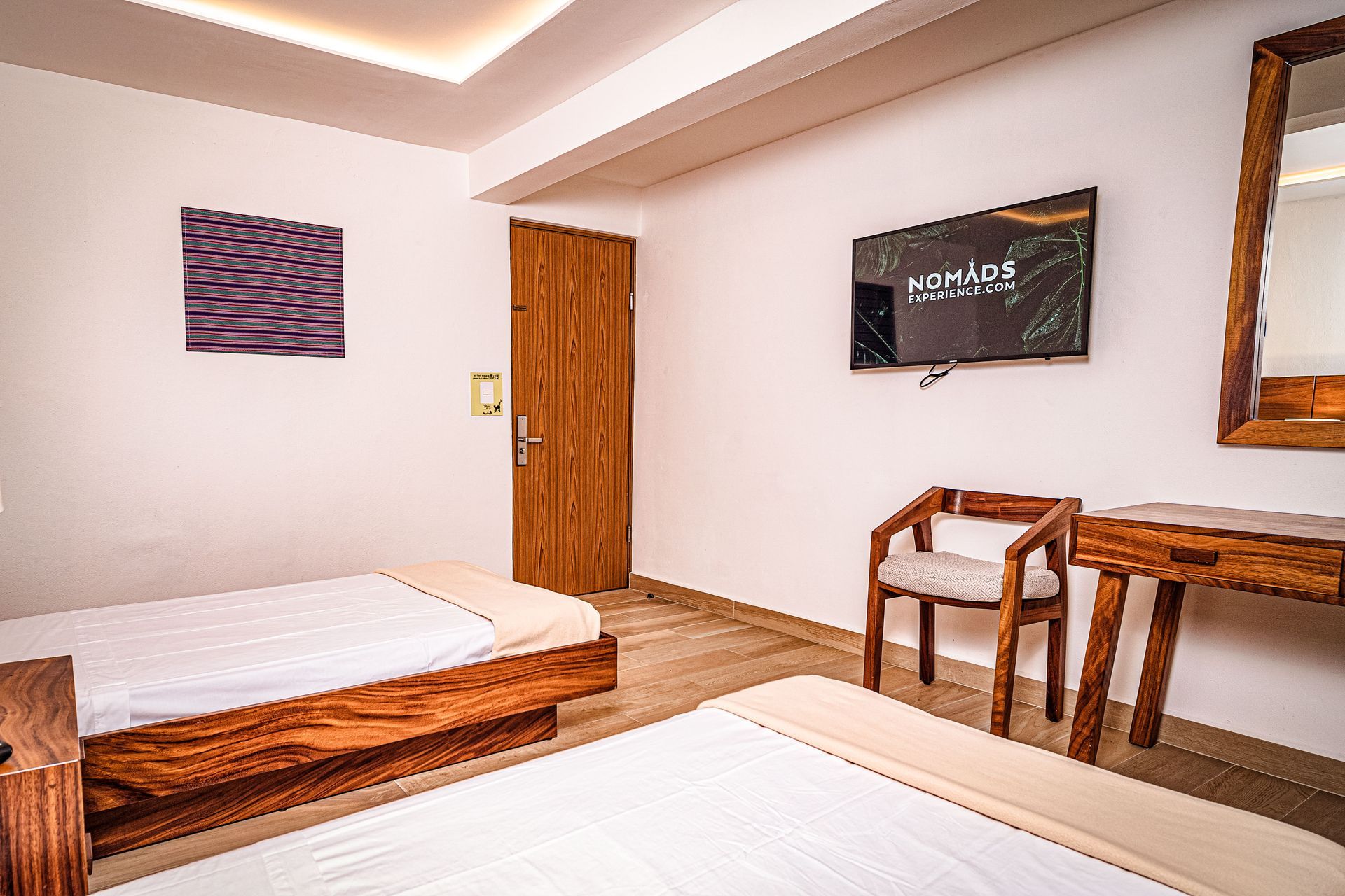 A hotel room with two beds , a chair and a flat screen tv.