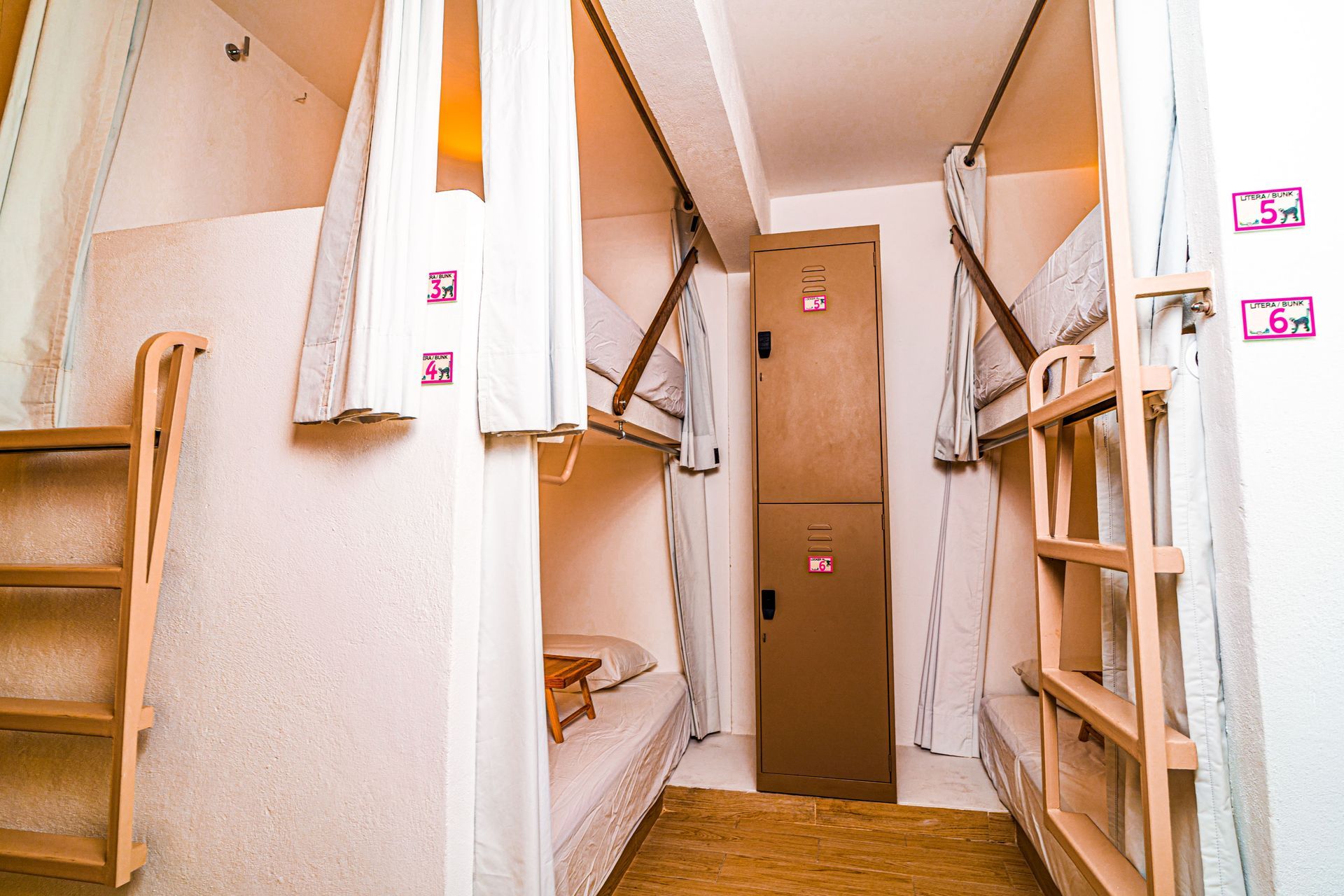 A room with bunk beds , a ladder and a locker.