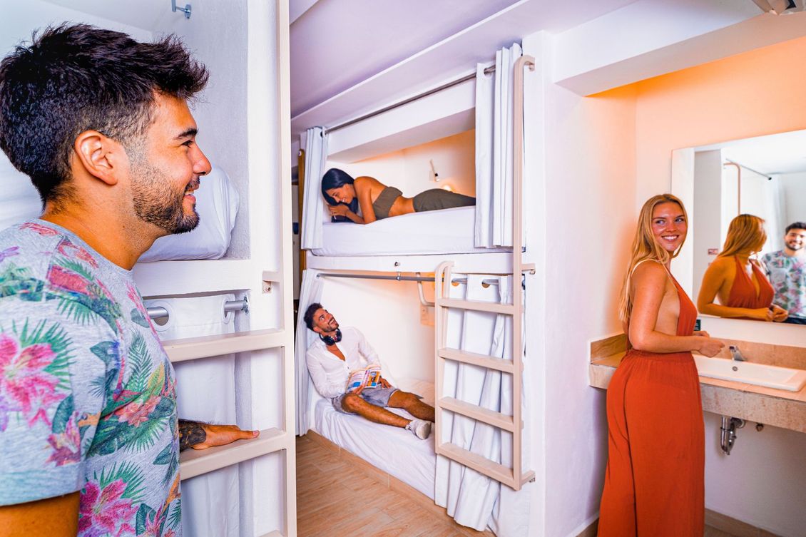 A man and a woman are standing in a room with bunk beds.