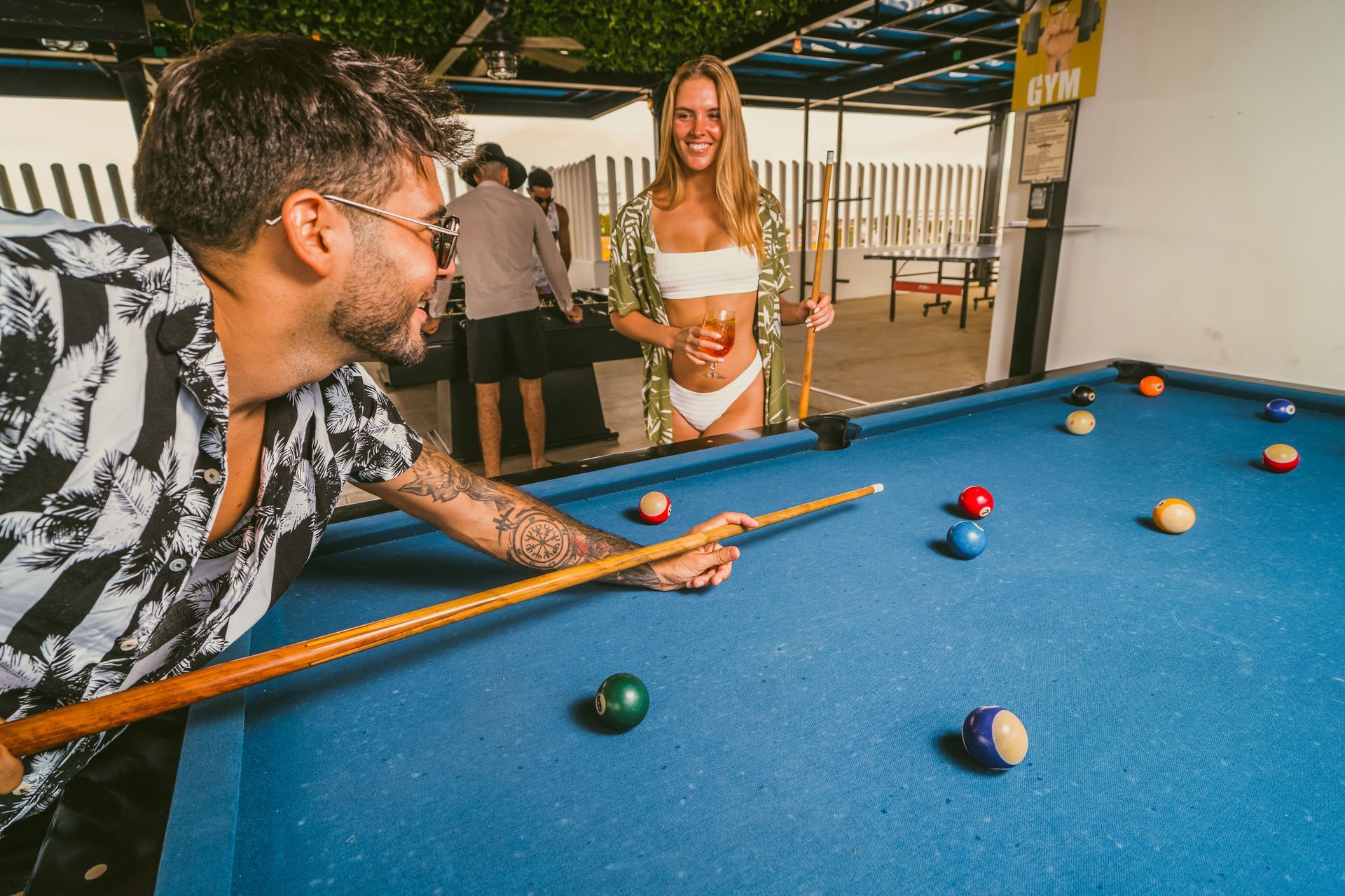 A man and a woman are playing pool on a pool table.