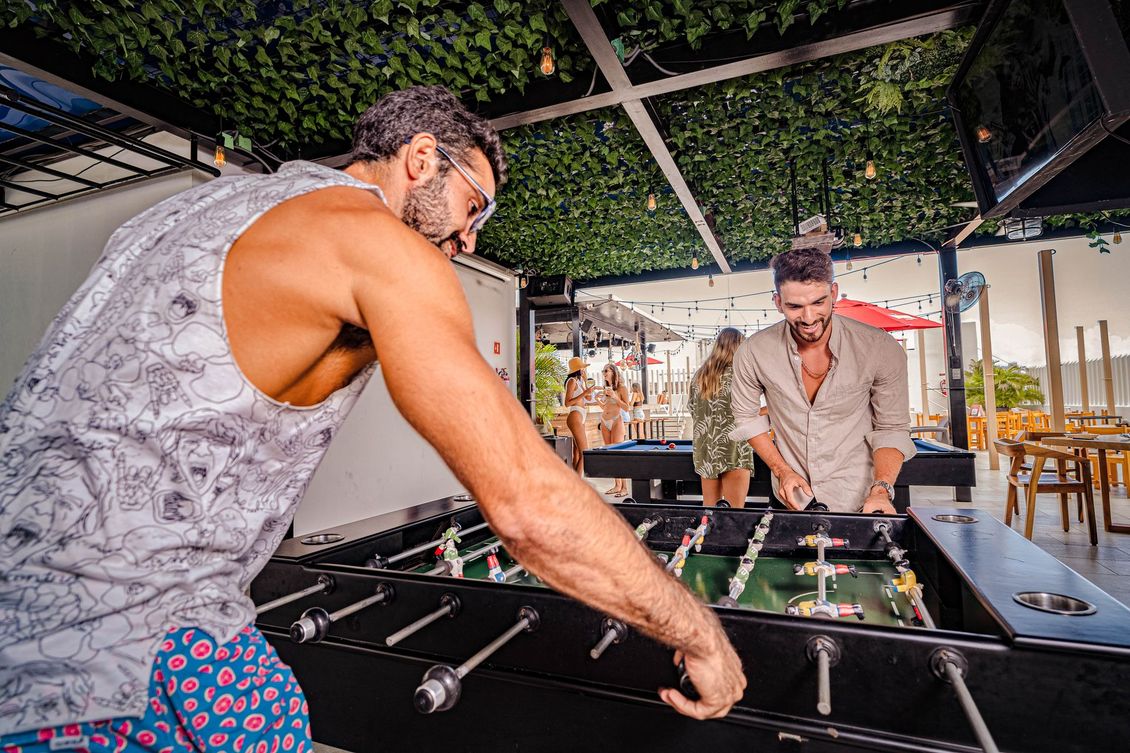 Two men are playing a game of foosball on a table.