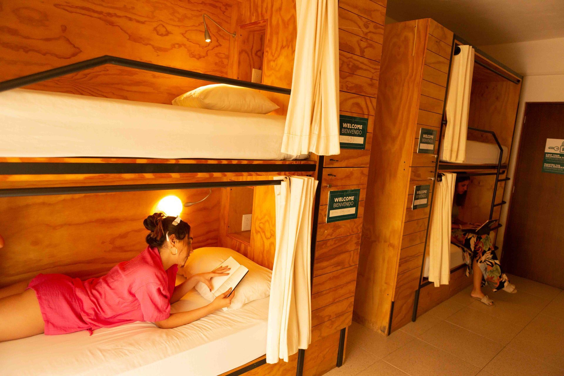 A woman is laying on a bunk bed in a dorm room.