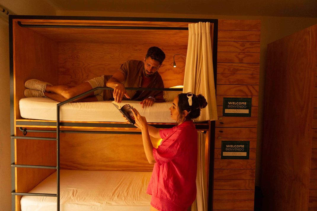 A man and a woman are standing next to a bunk bed.