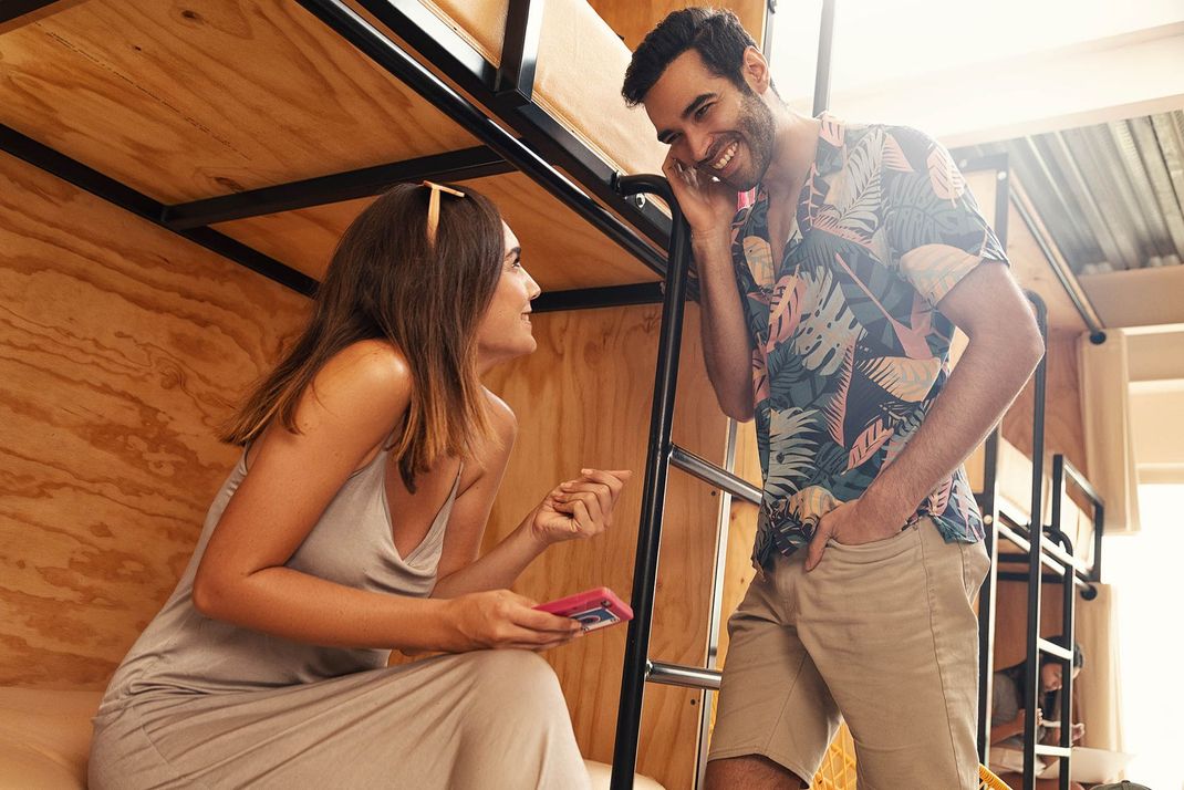 A man and a woman are talking to each other in a bunk bed.