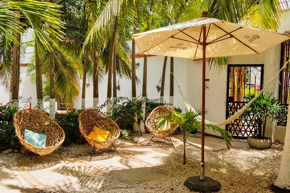 A patio with wicker chairs , an umbrella and a hammock.