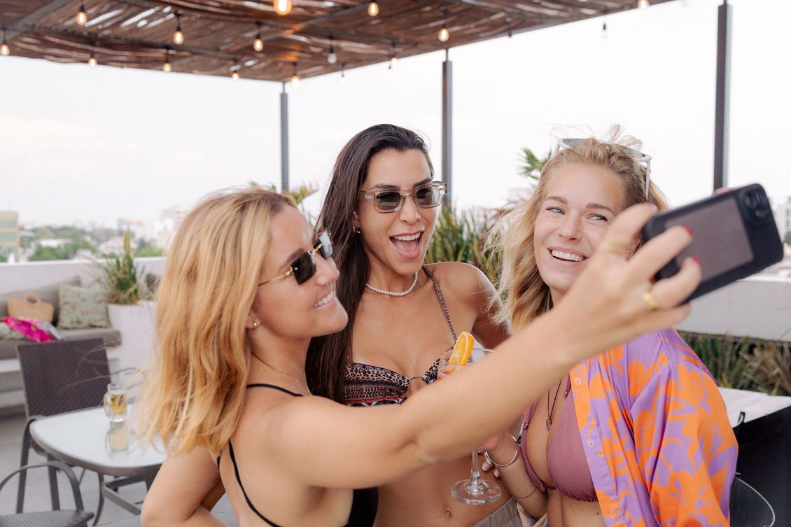 Three women are taking a selfie together on a rooftop.