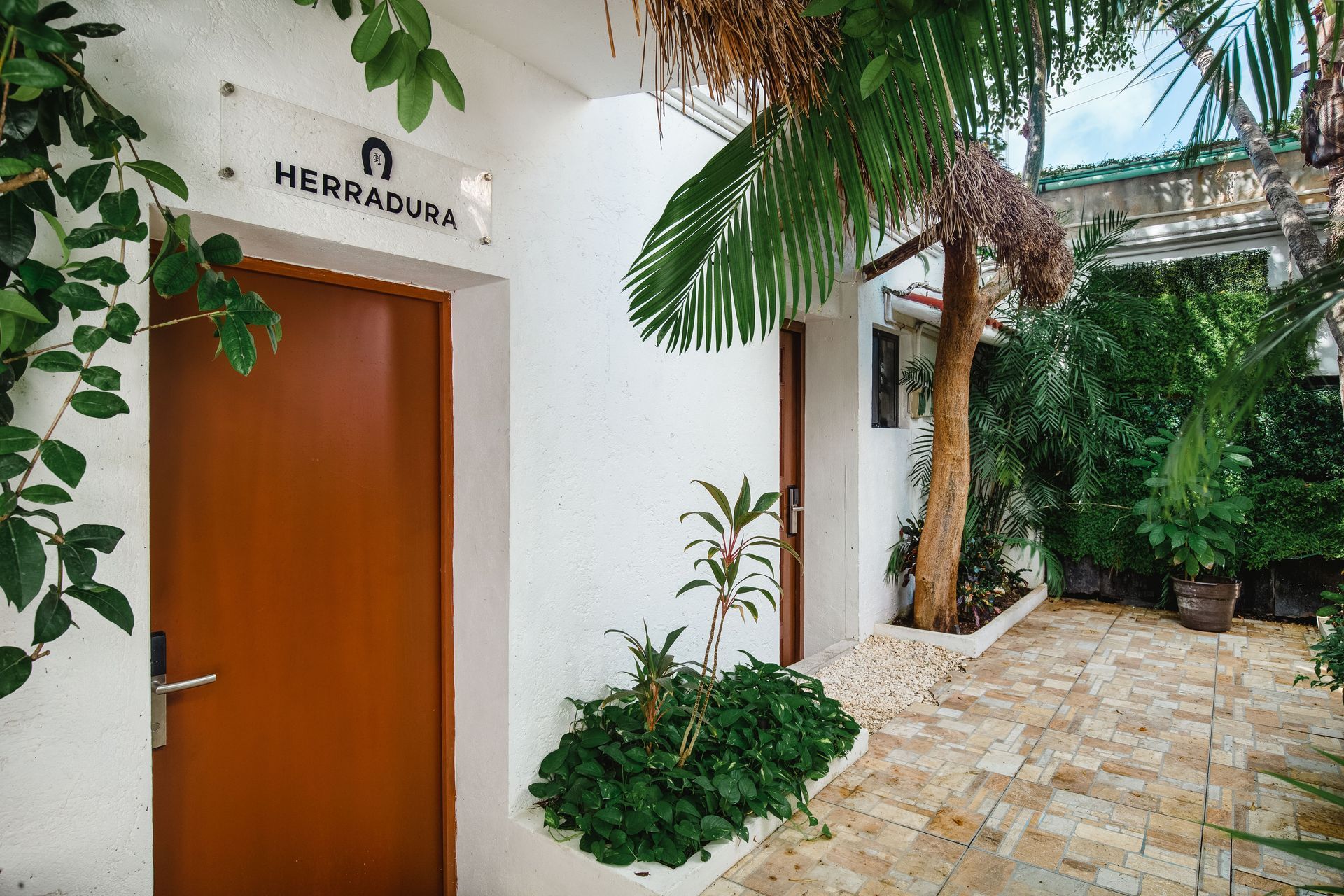 A white building with a brown door and a sign that says herradura