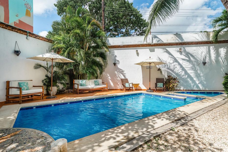 There is a large swimming pool with umbrellas and chairs around it.