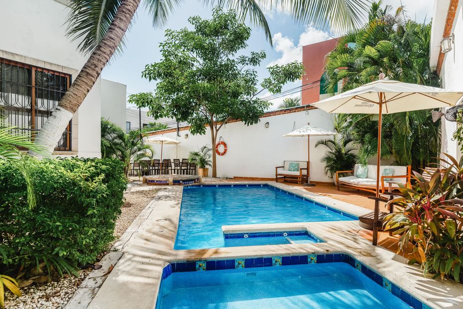 A large swimming pool with umbrellas and chairs around it.