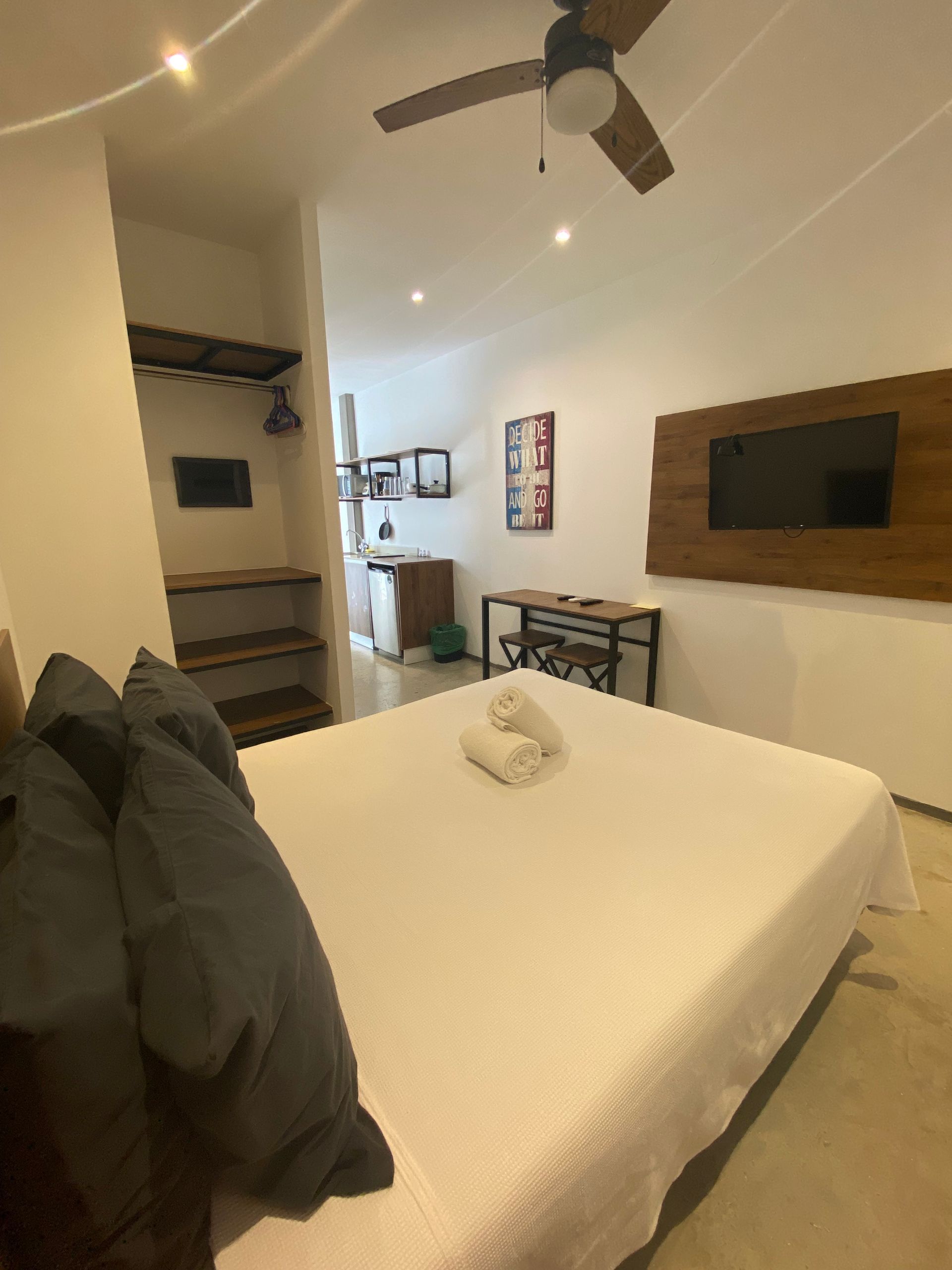 A bedroom with a bed , ceiling fan and television.