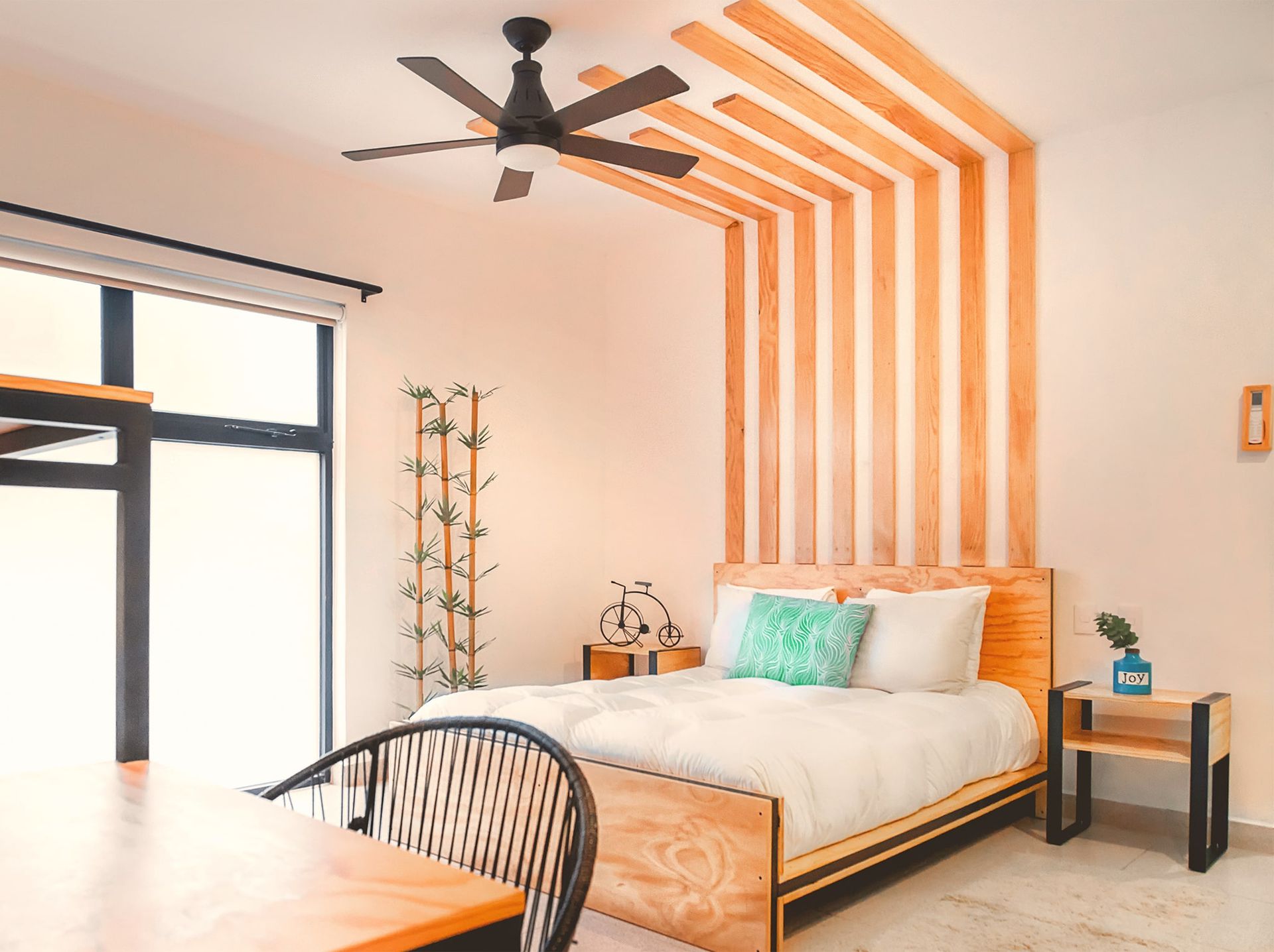 A bedroom with a bed , table and chairs and a ceiling fan.