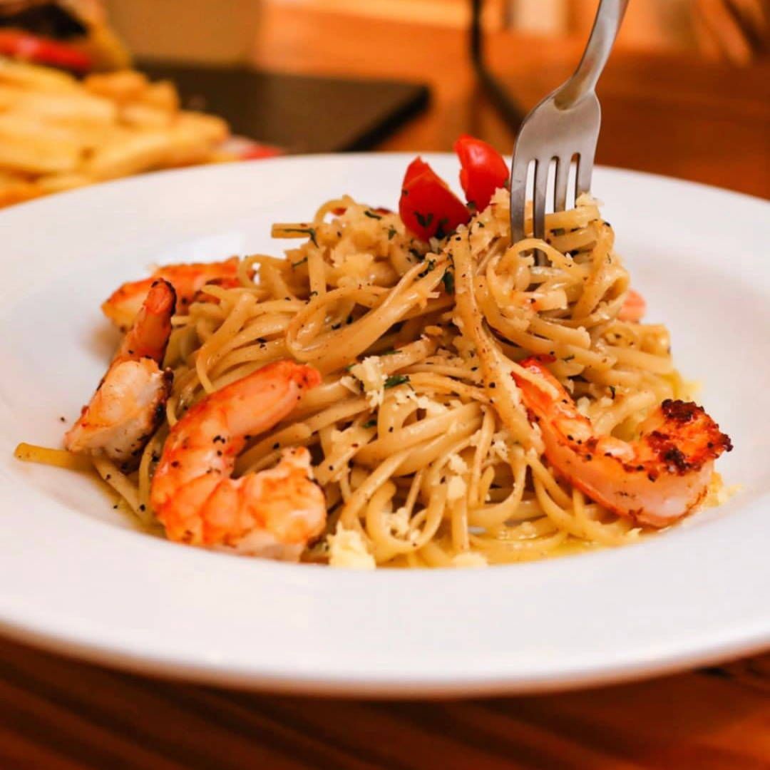 A plate of spaghetti with shrimp and tomatoes with a fork sticking out of it