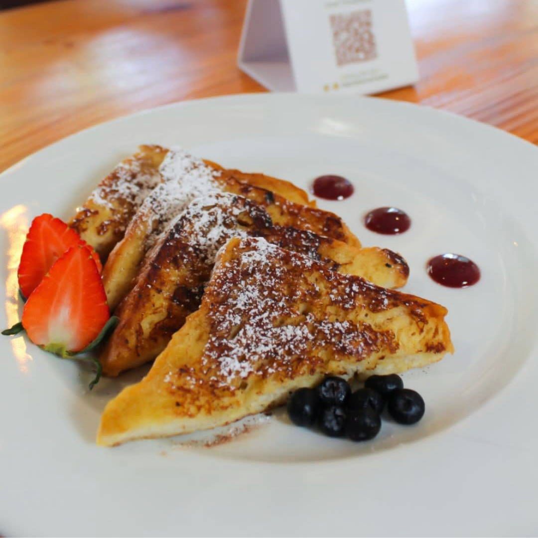 A white plate topped with french toast strawberries and blueberries