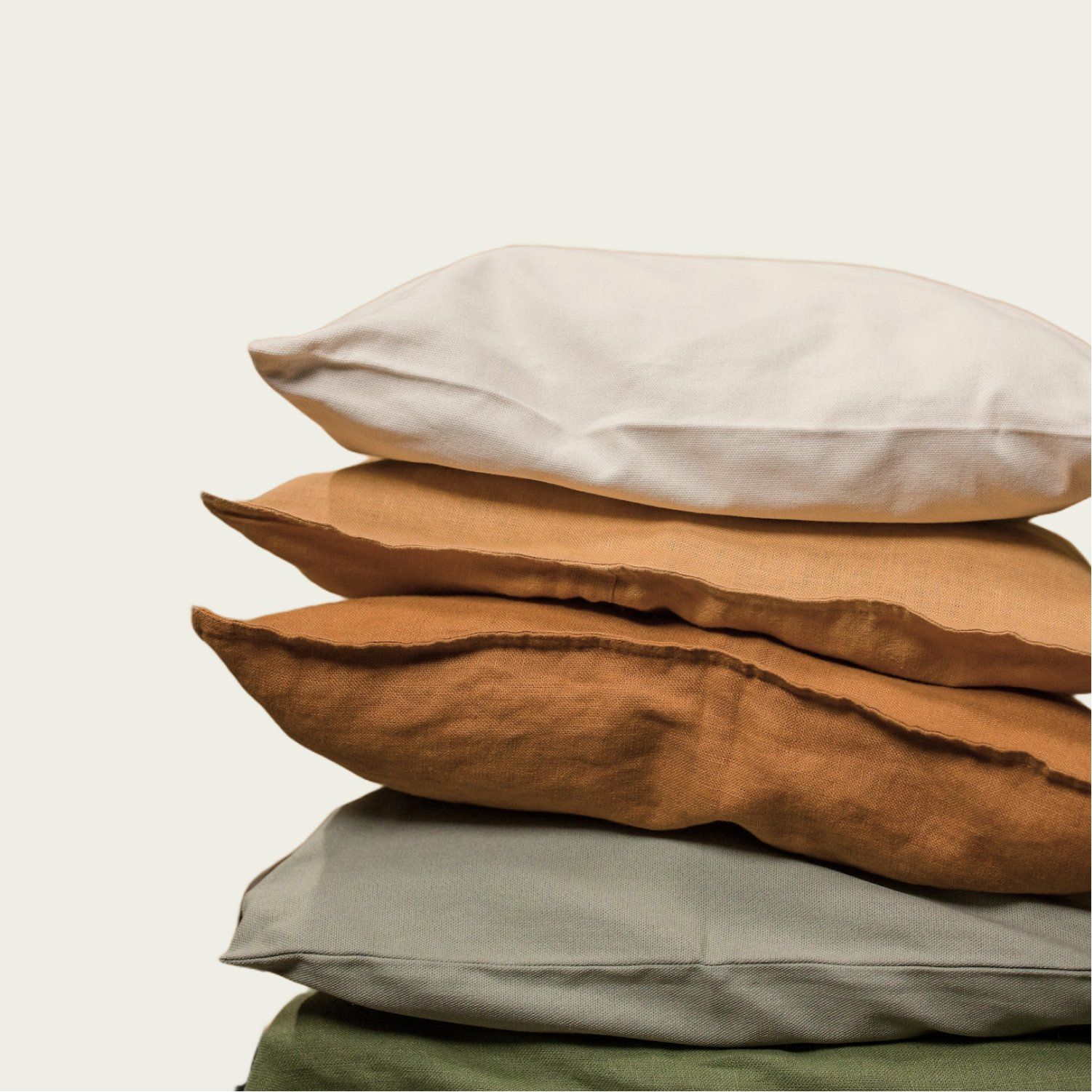 Pile of five textured square pillows in neutral colors.