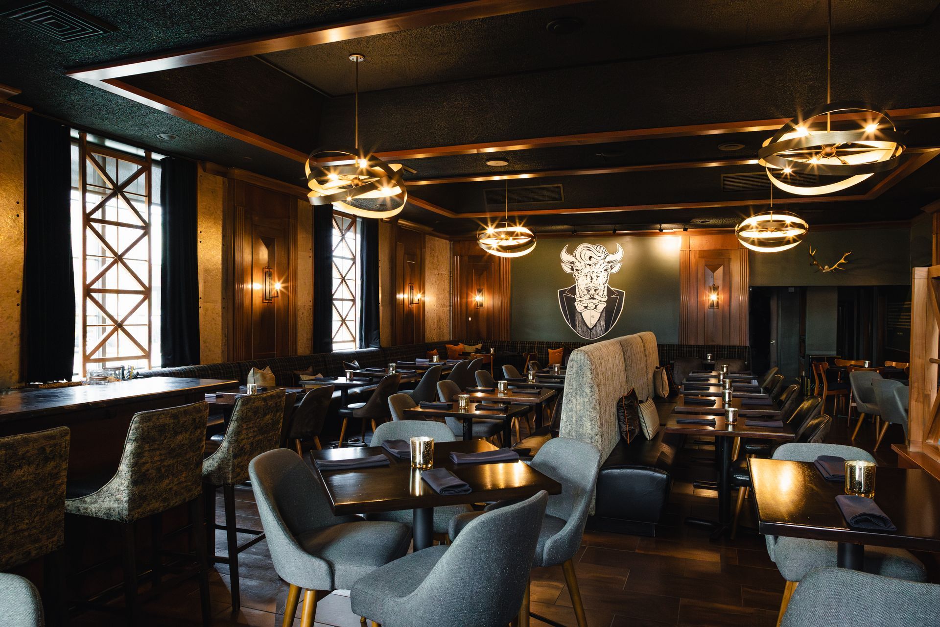 Restaurant interior with tables and chairs, decorative lighting, dark walls and bar.