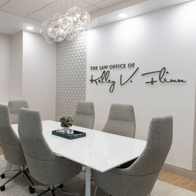 Conference room with white table, gray chairs, TV, and decorative wall.