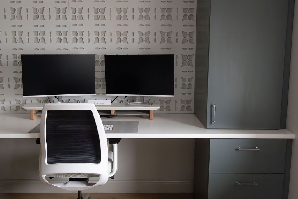 Office interior with people working at desks, casual seating, and large windows.