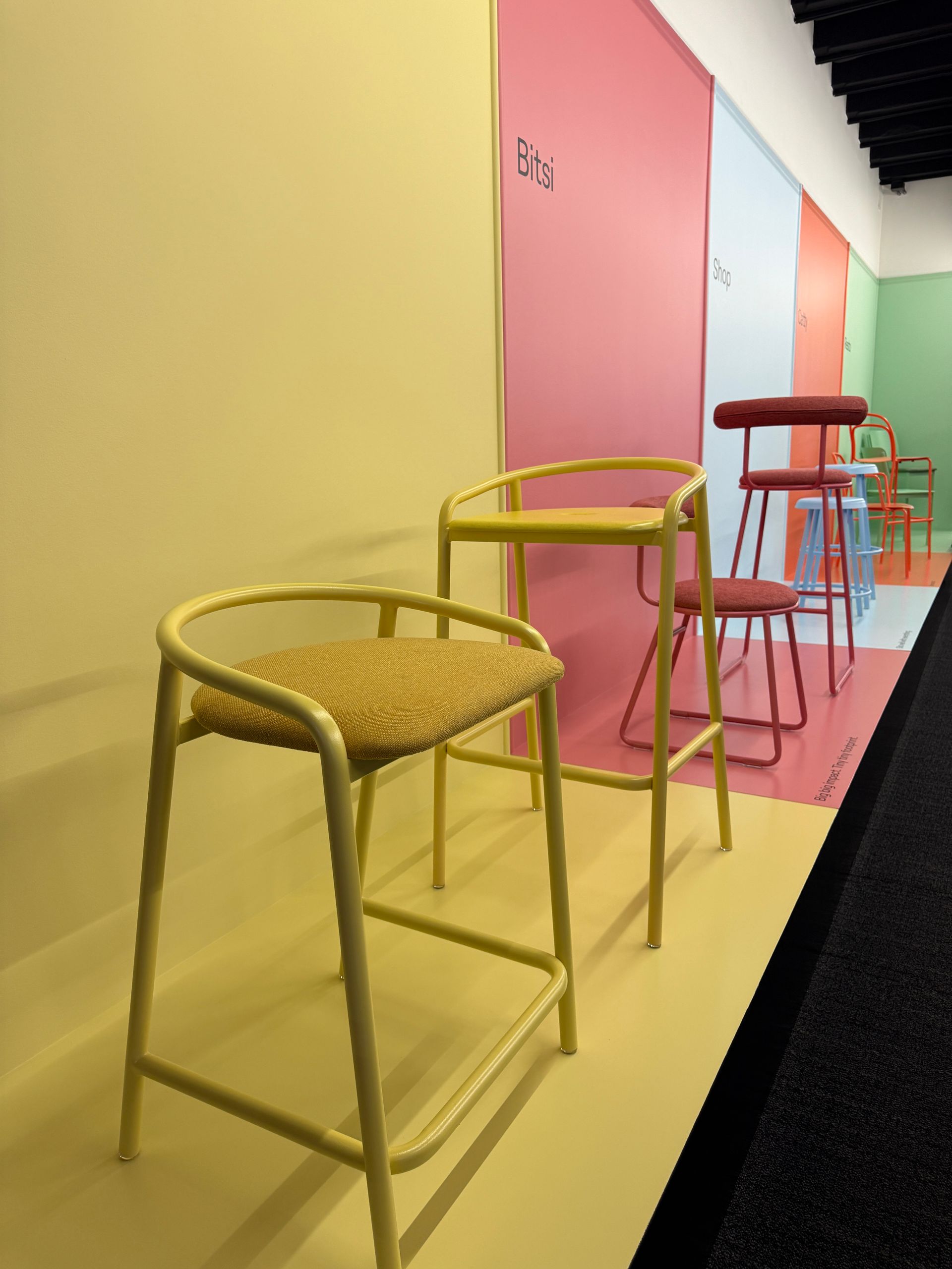Row of colorful stools along a pastel wall in a modern interior