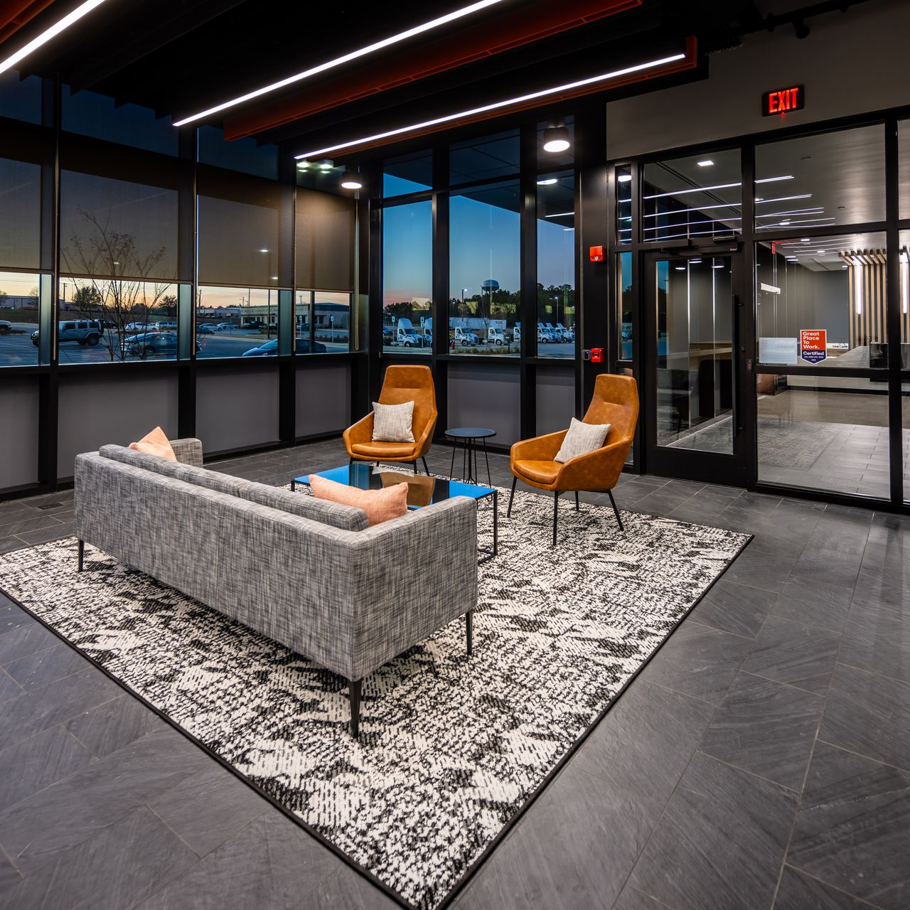 Office space with cubicles, computers, and black chairs. Wooden and gray dividers.