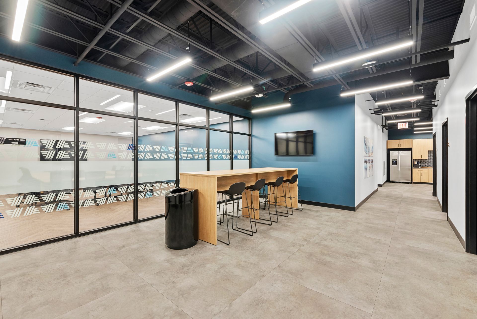 Lounge area with orange chairs, wood-paneled wall with vertical greenery, and decorative hanging lights.