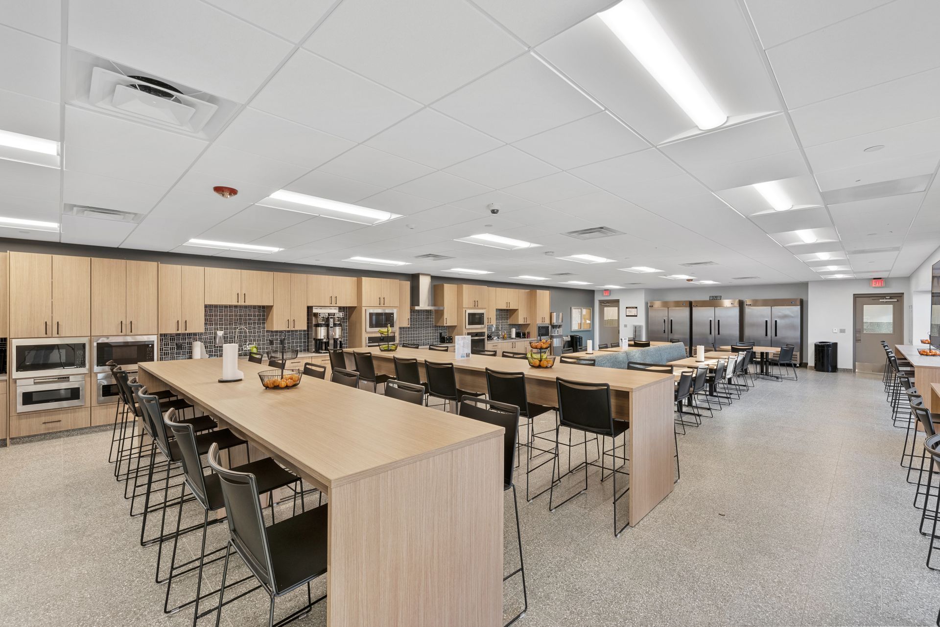 Commercial kitchen with long island counters, appliances, and bar stools.
