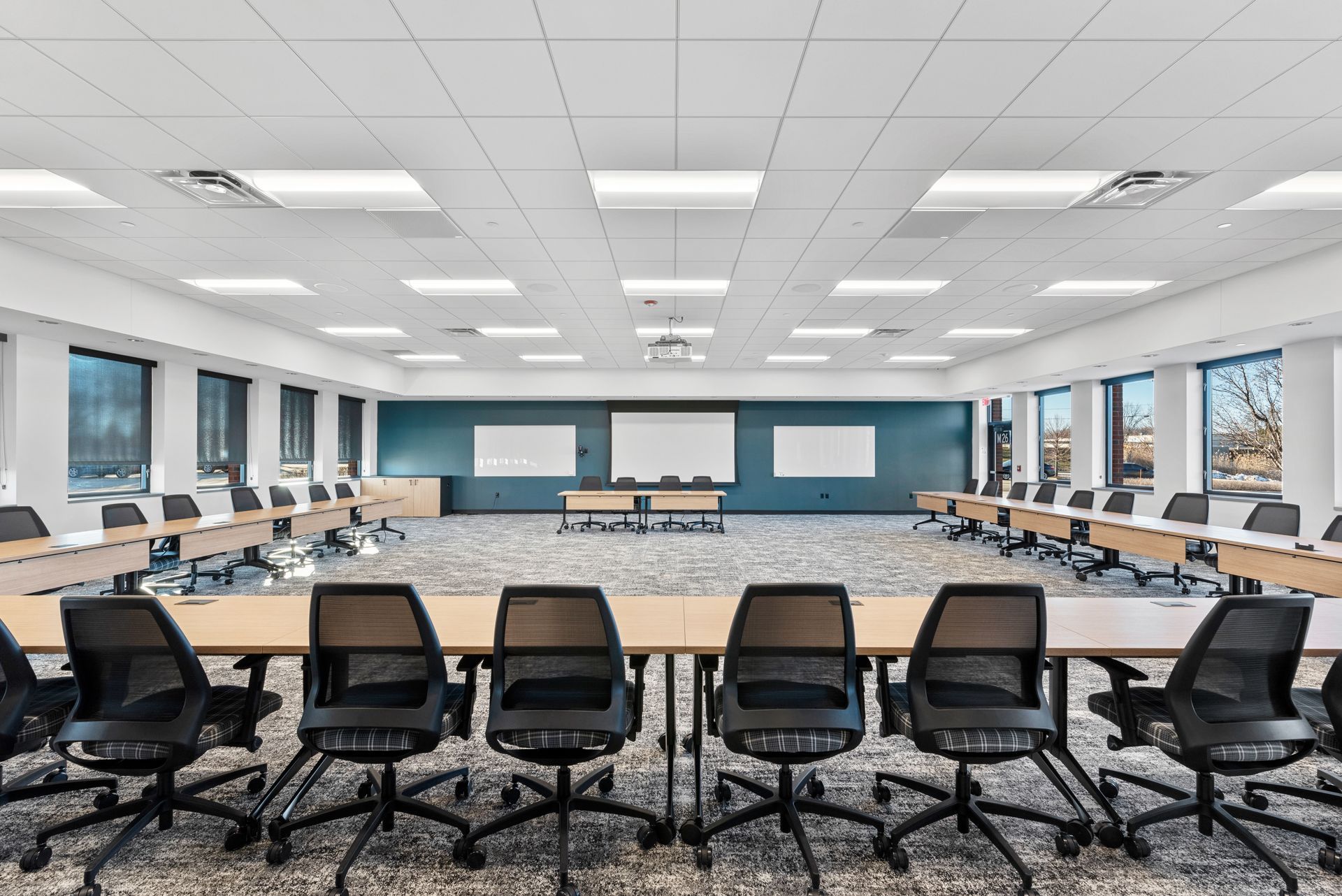 Conference room with U-shaped table, black chairs, and projection screen.