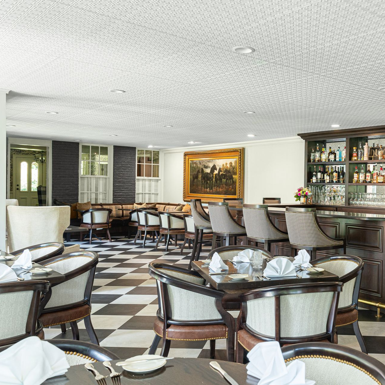 Elegant restaurant dining room with checkered floor, set tables, wicker chairs, and wall art