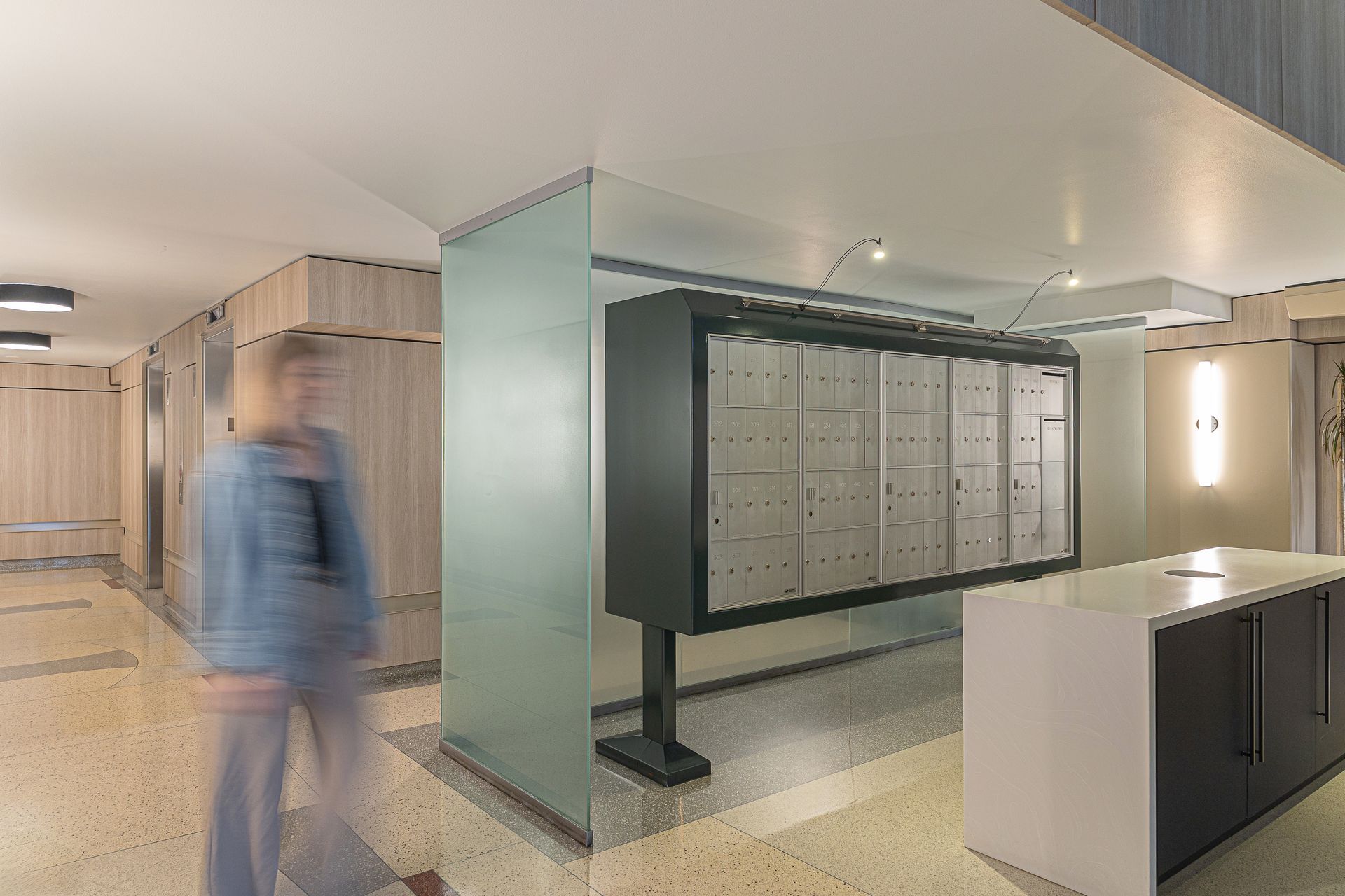 Hallway with mailboxes and a blurry person walking by.