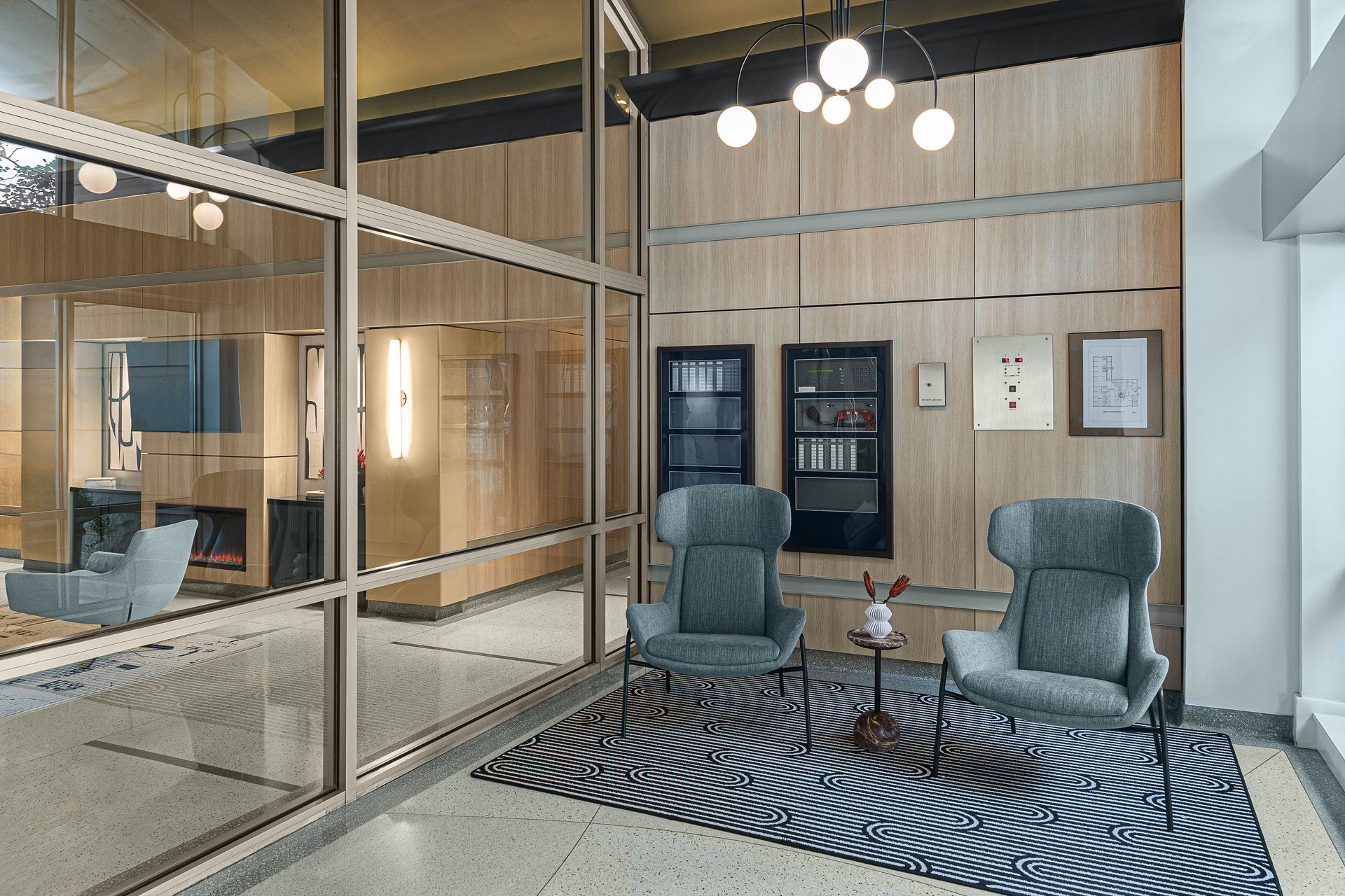 Interior with gray armchairs, zebra rug, glass walls, wooden paneling, and globe lights.