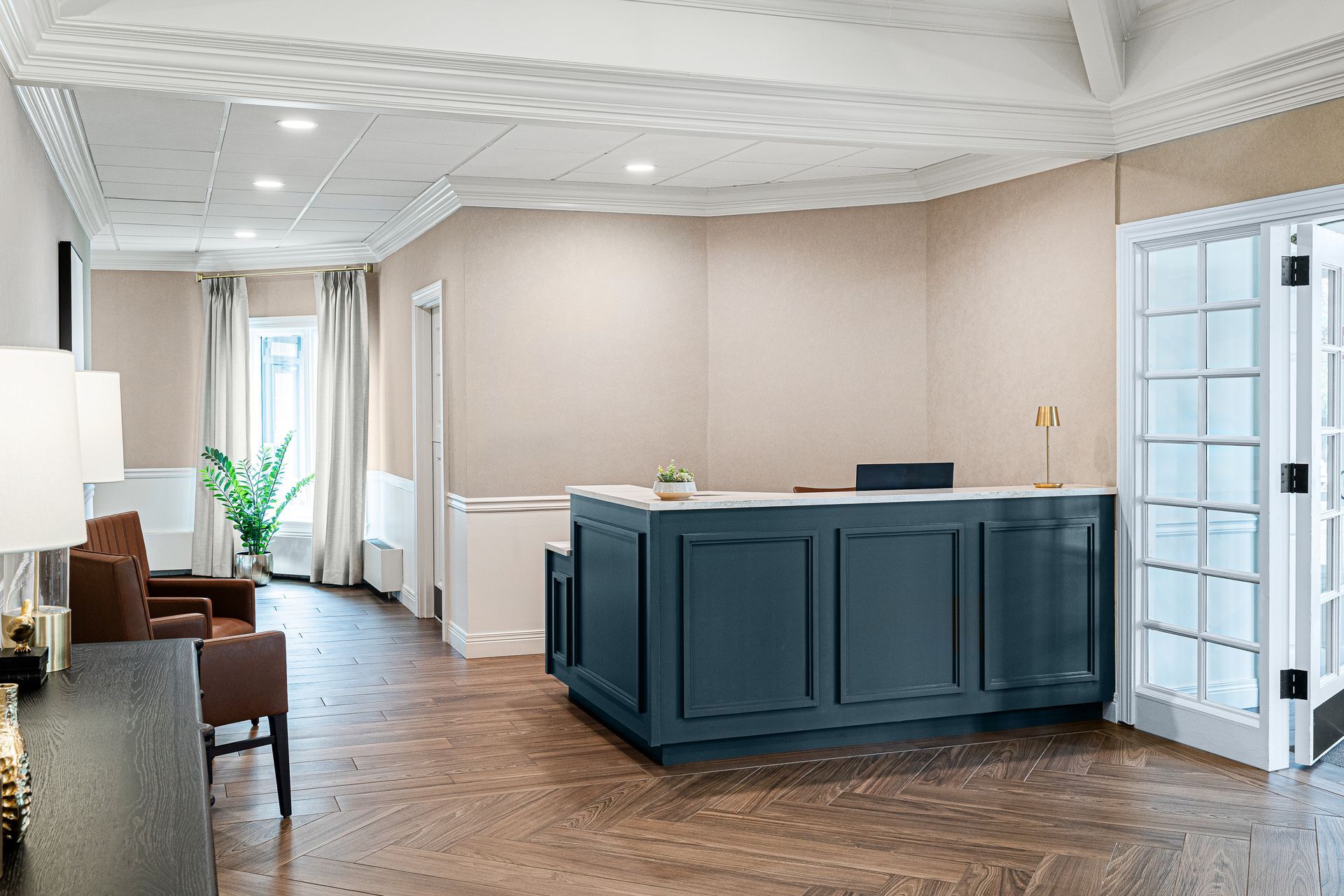 Reception desk in a waiting area with a teal counter, wood floors, and white walls.
