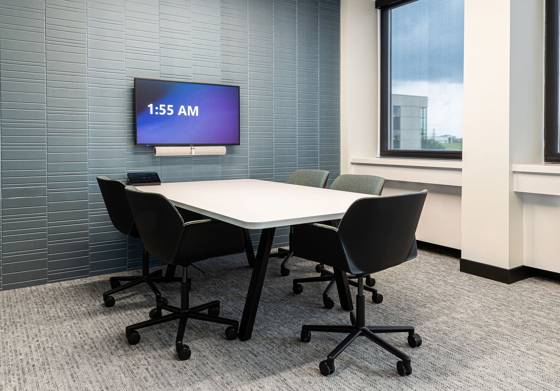 Meeting room with table, chairs, TV displaying 1:53 AM, and window.