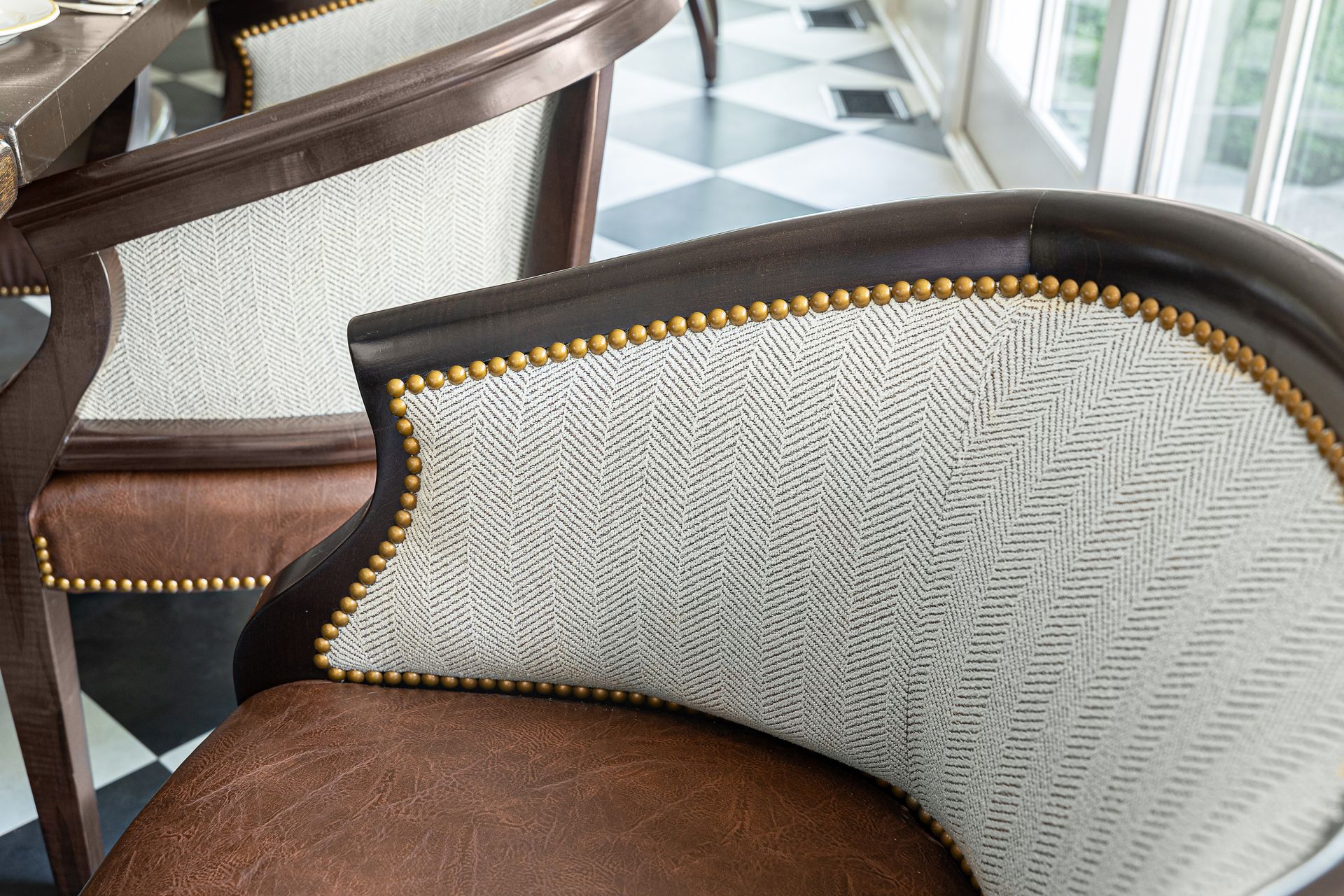 Two brown and cream upholstered chairs in a room with a checkered floor.
