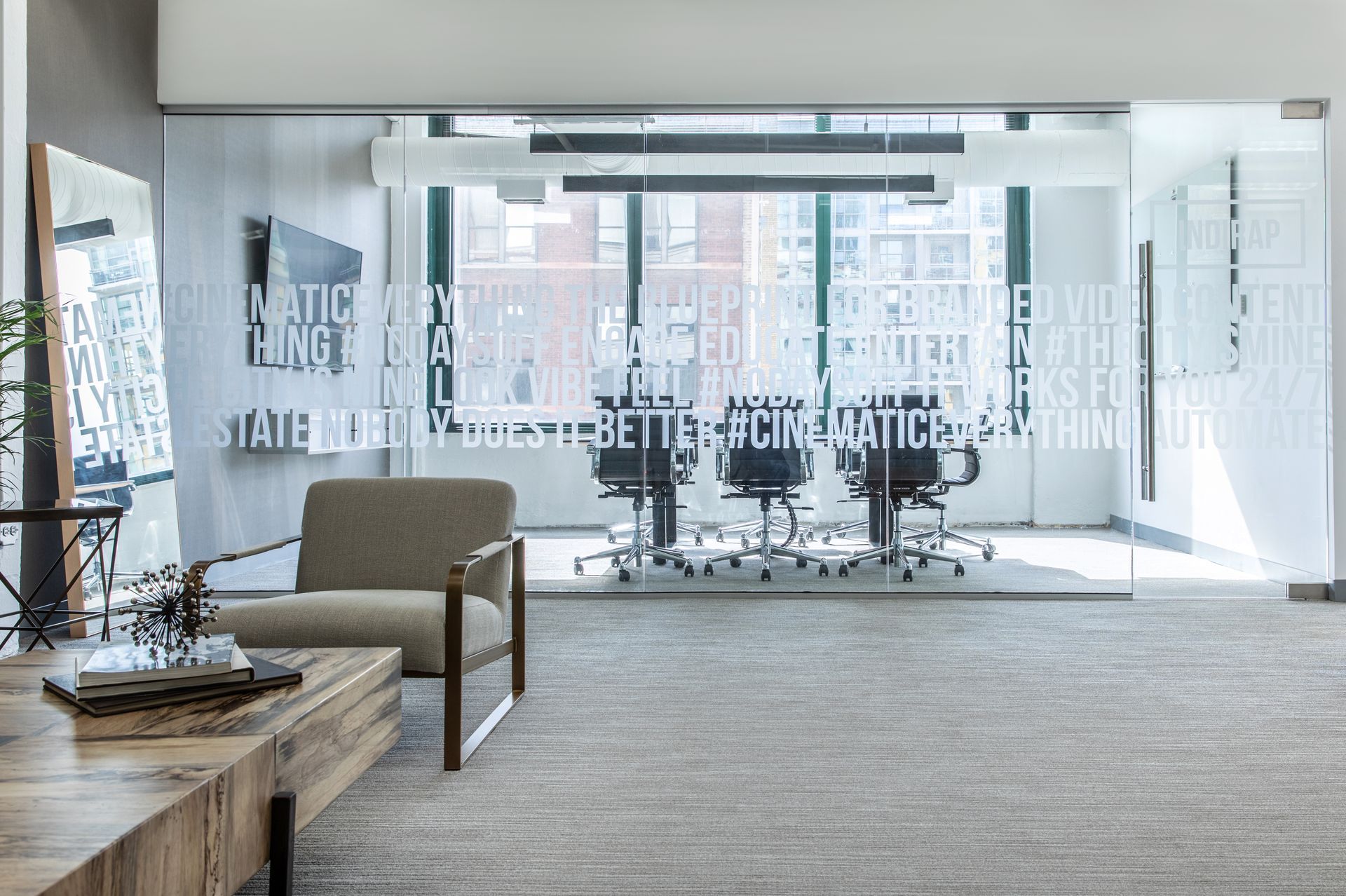 A modern office lobby with a waiting area and a glass-walled conference room.