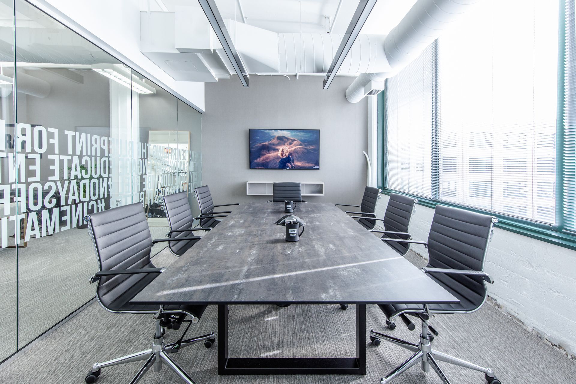Lounge area with tan leather chairs, a fireplace, artwork, and a black and white rug.