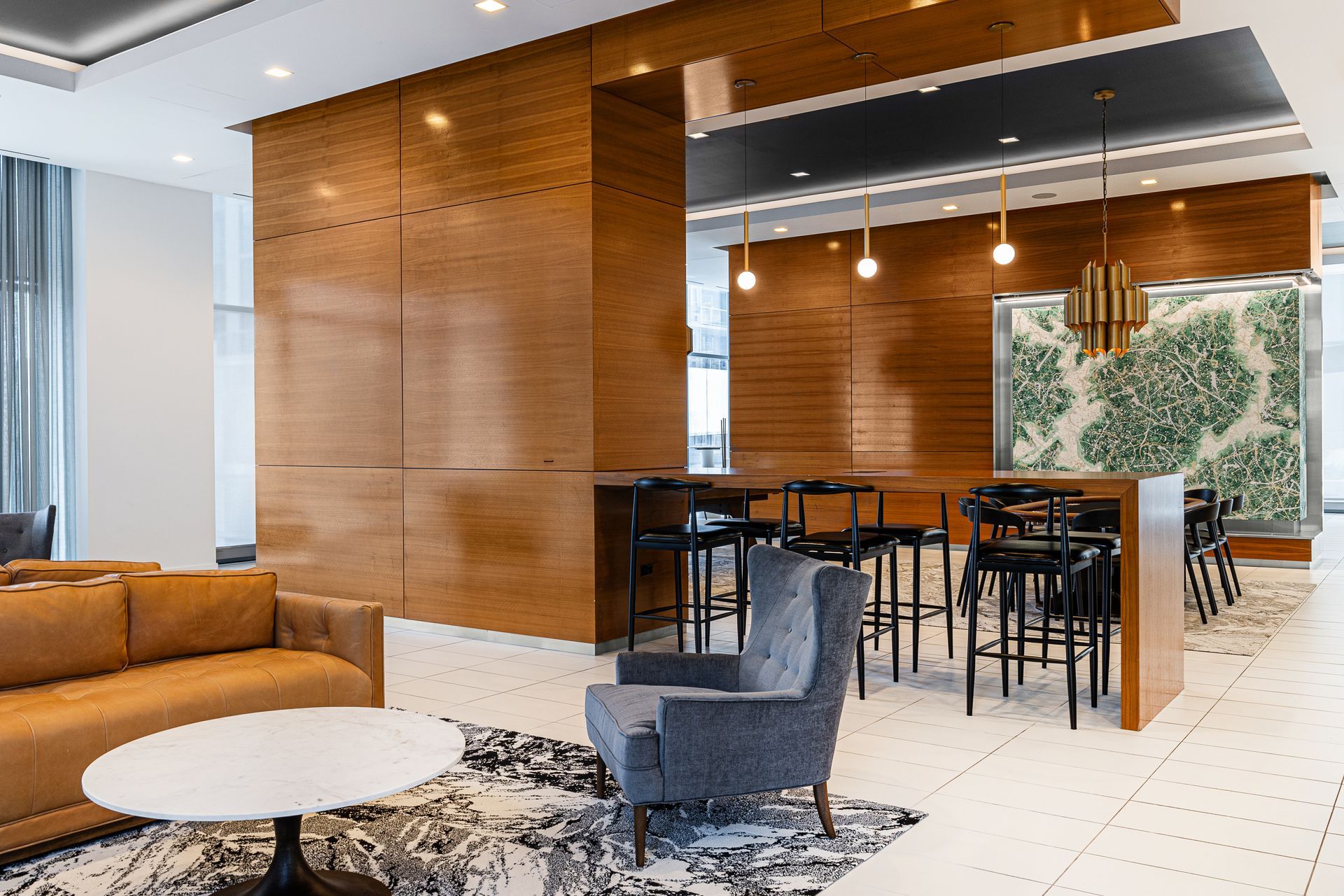 Lounge area with brown wood paneling, seating, bar stools, and a decorative map-like piece.